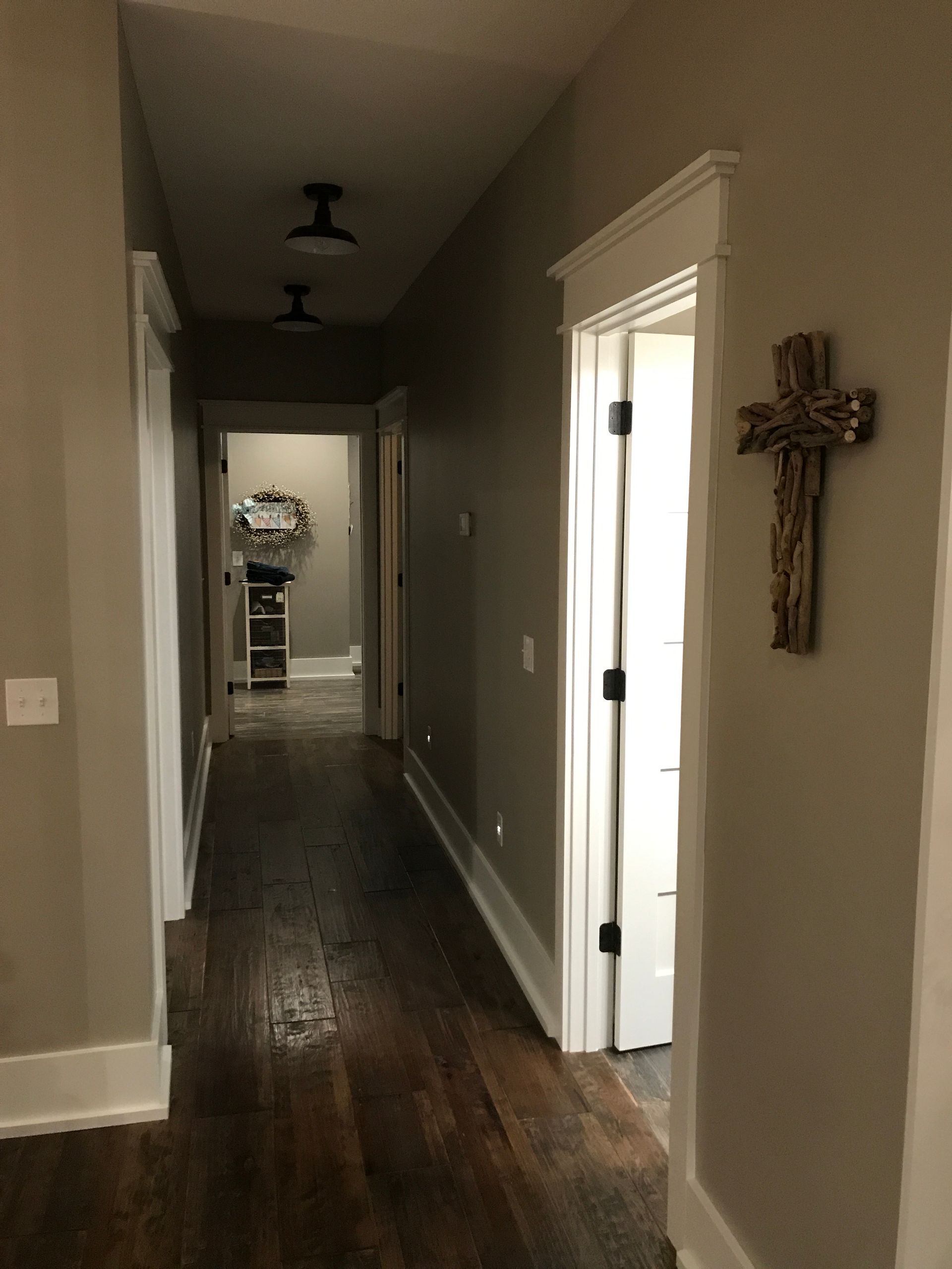A long hallway with wooden floors and a cross on the wall.