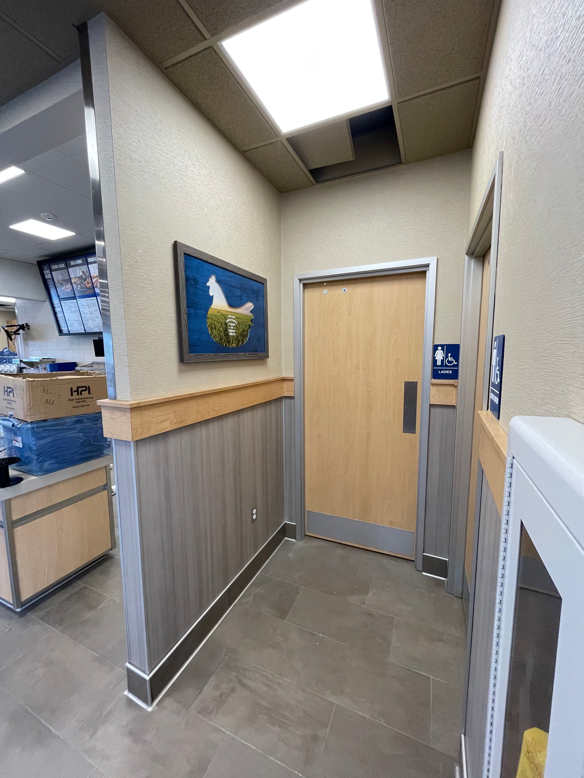 A hallway in a restaurant with a picture of a chicken on the wall
