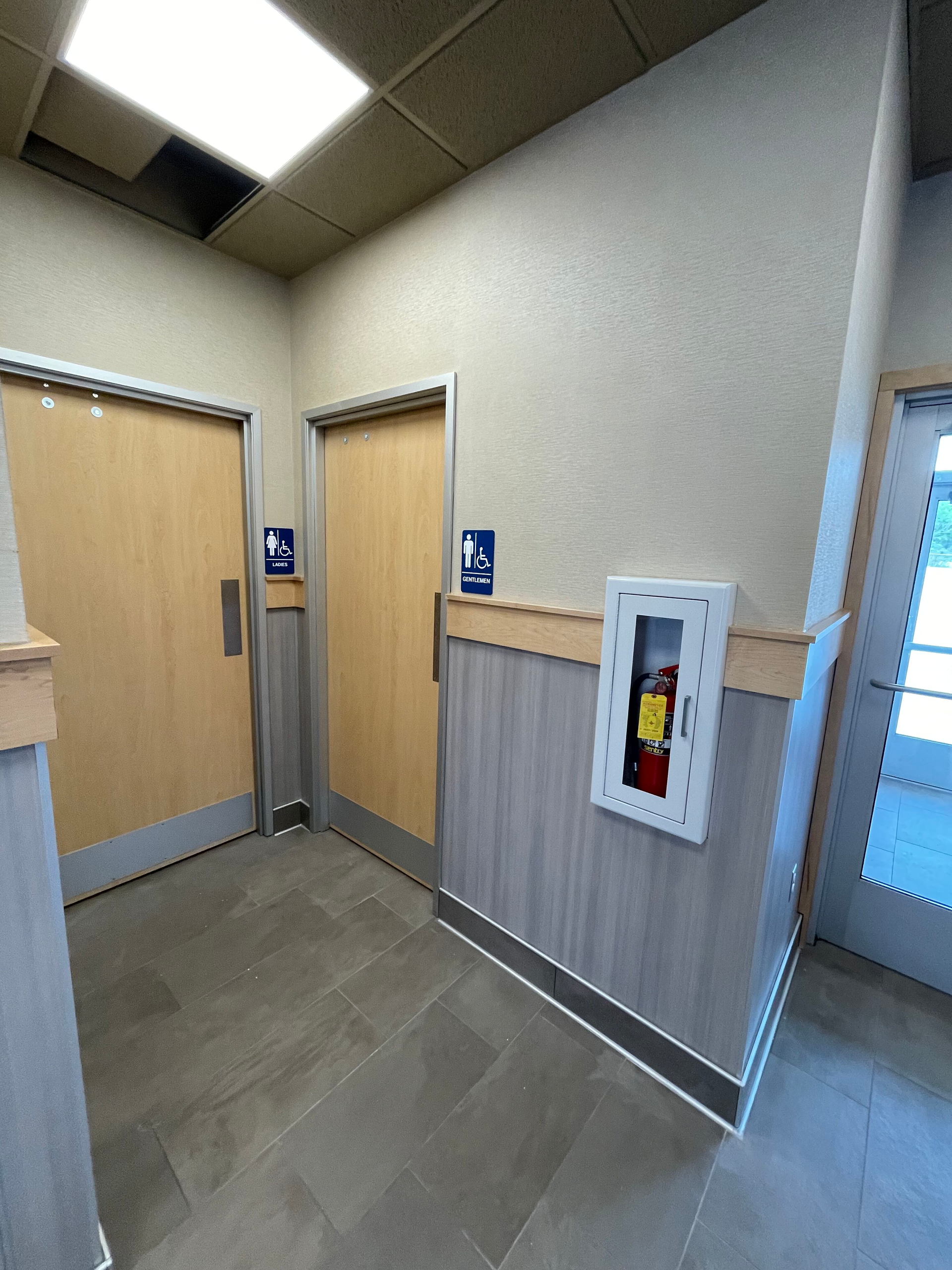 A hallway with two doors and a fire extinguisher on the wall