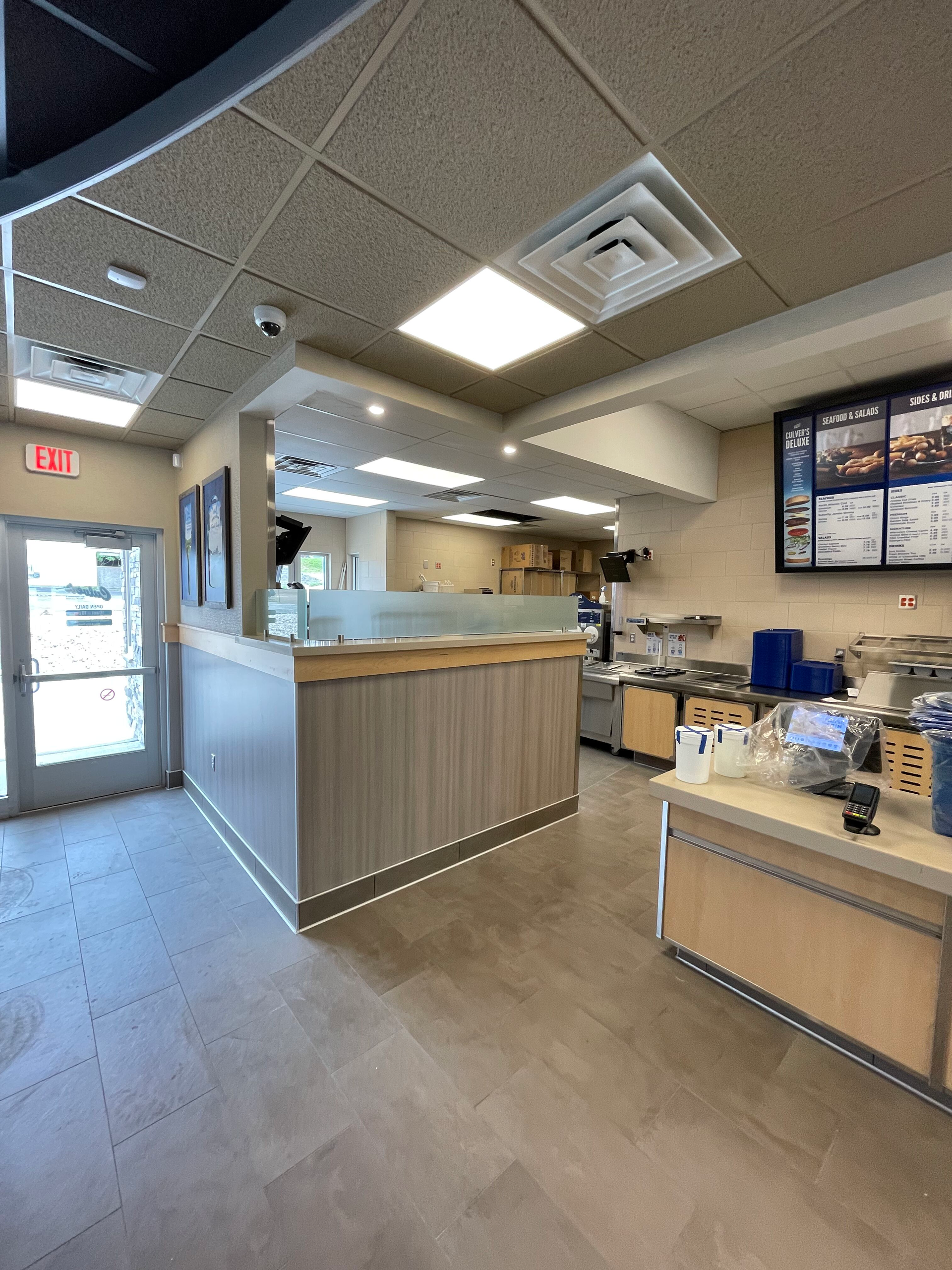A restaurant with a counter and a menu on the wall.
