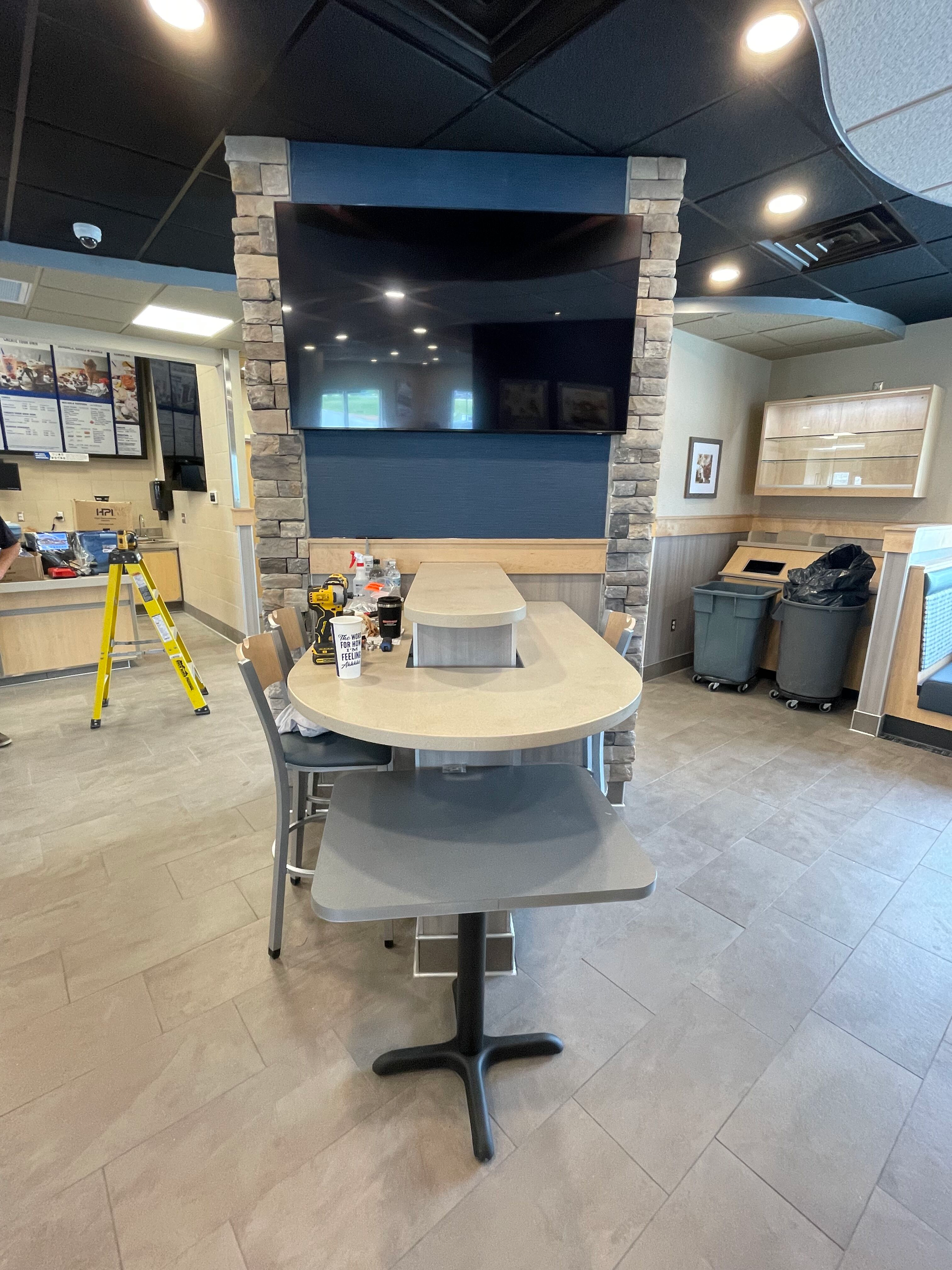 A room with a table and chairs and a television on the wall.