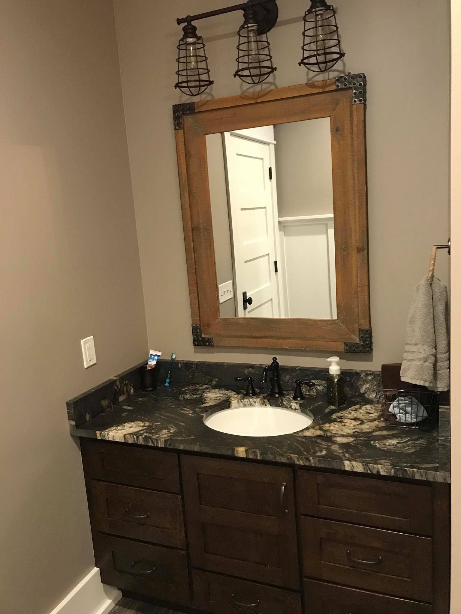A bathroom with a sink , mirror and drawers.
