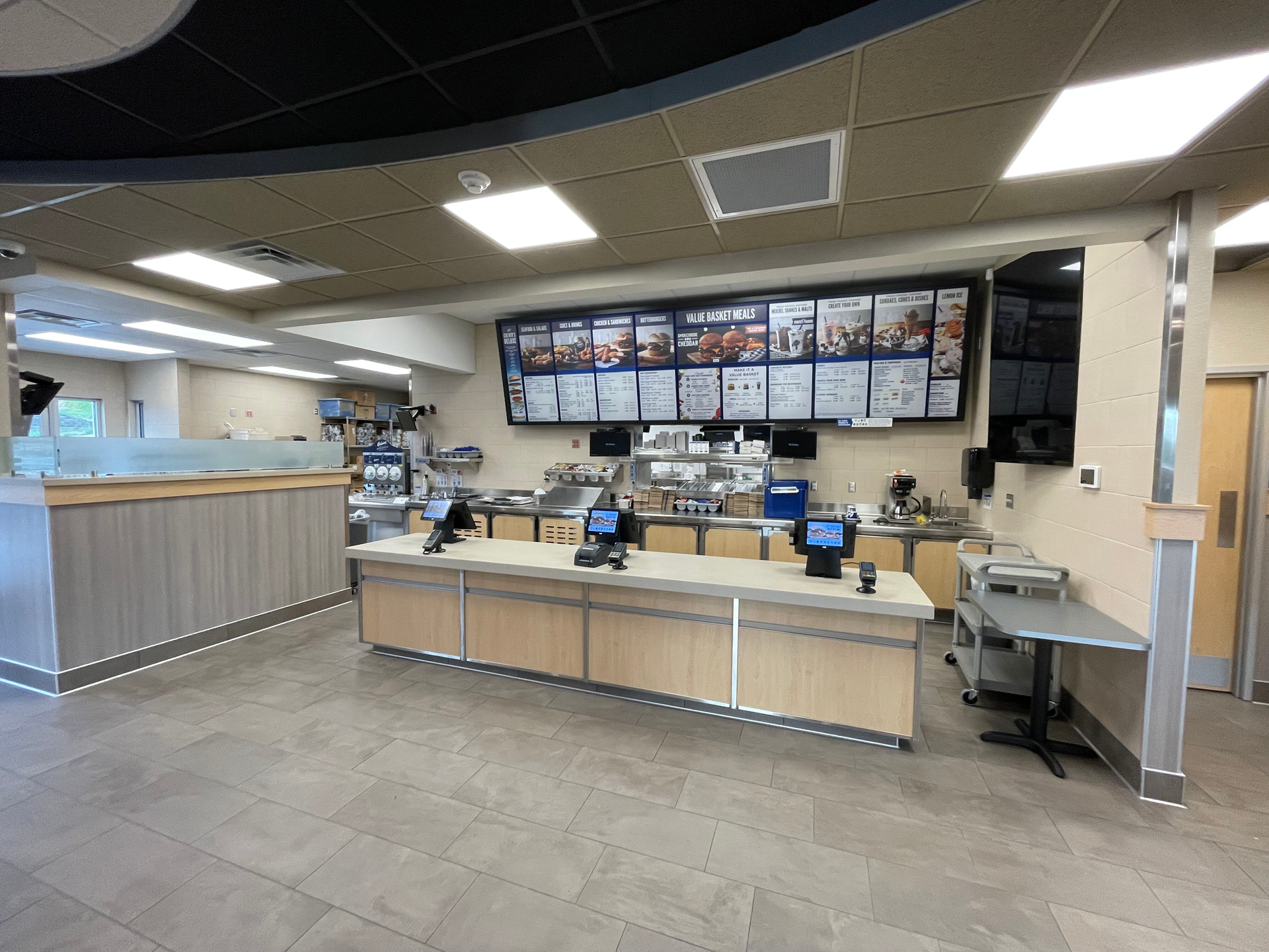A restaurant with a counter and a menu on the wall.