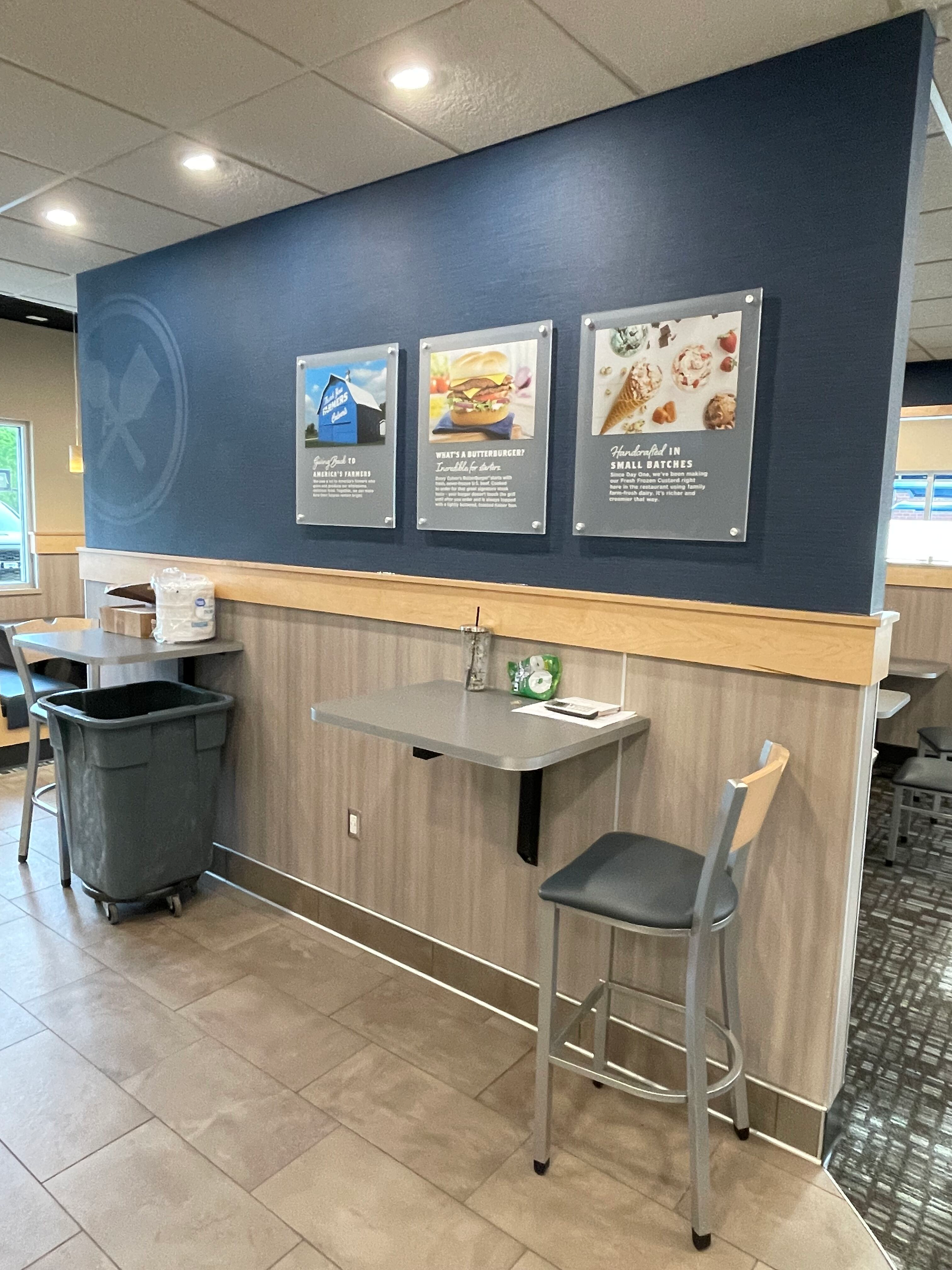 A restaurant with a table and chairs and a trash can.