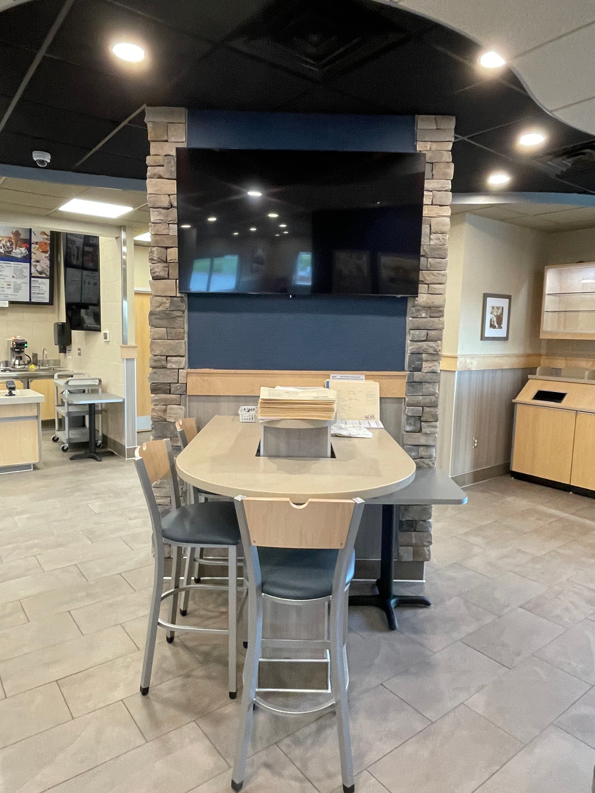 A restaurant with a table and chairs and a flat screen tv