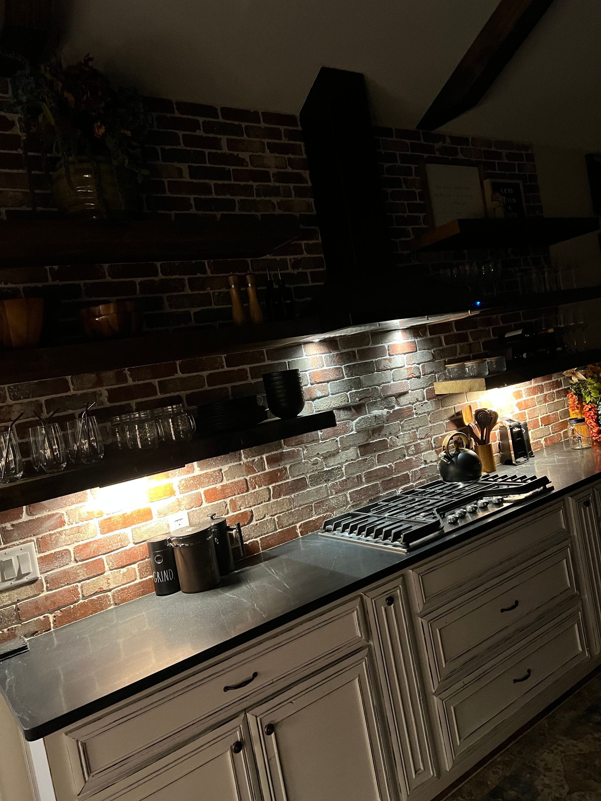 A kitchen with a stove top oven and a brick wall.