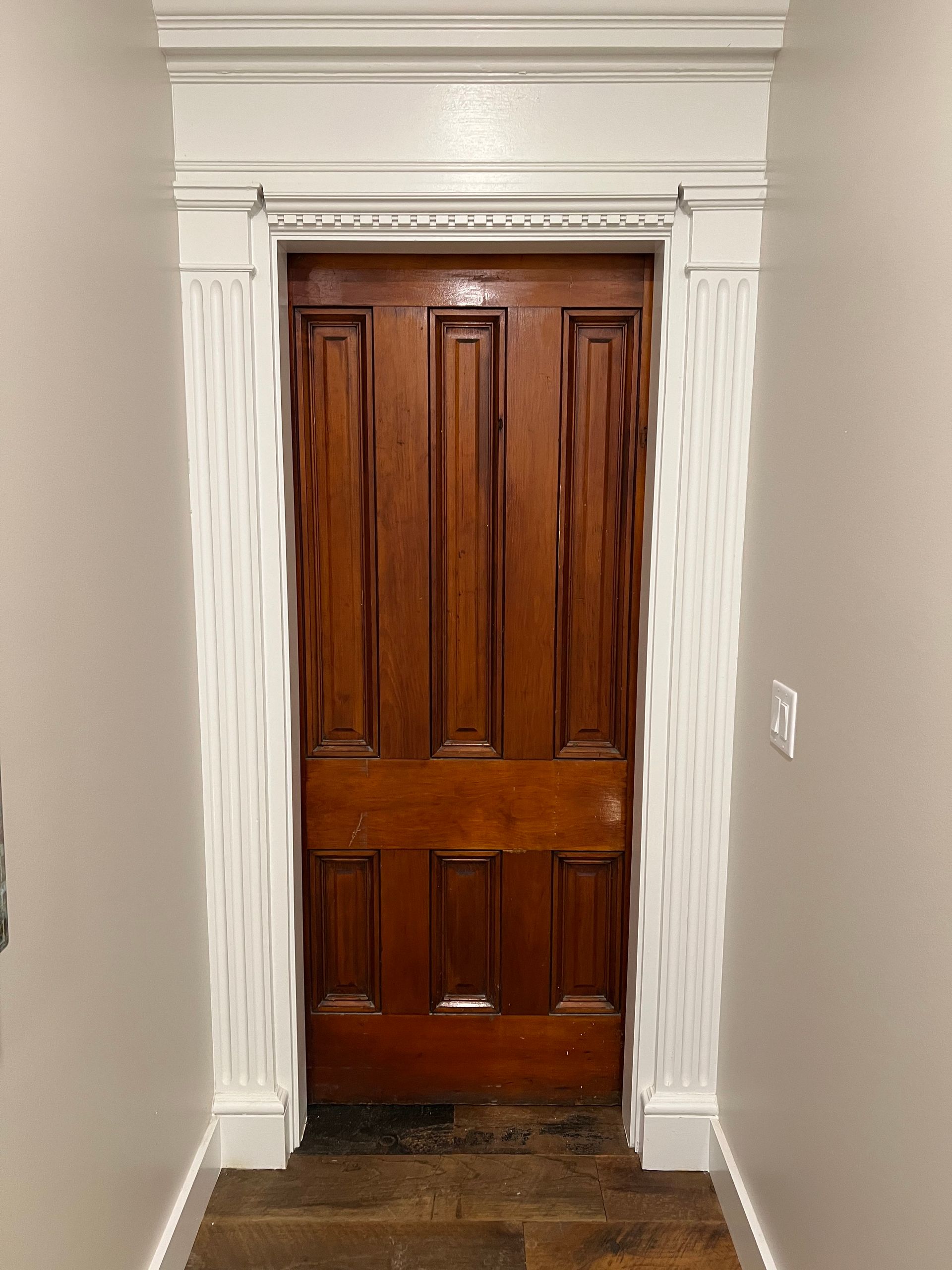 A hallway with a wooden door and white trim.