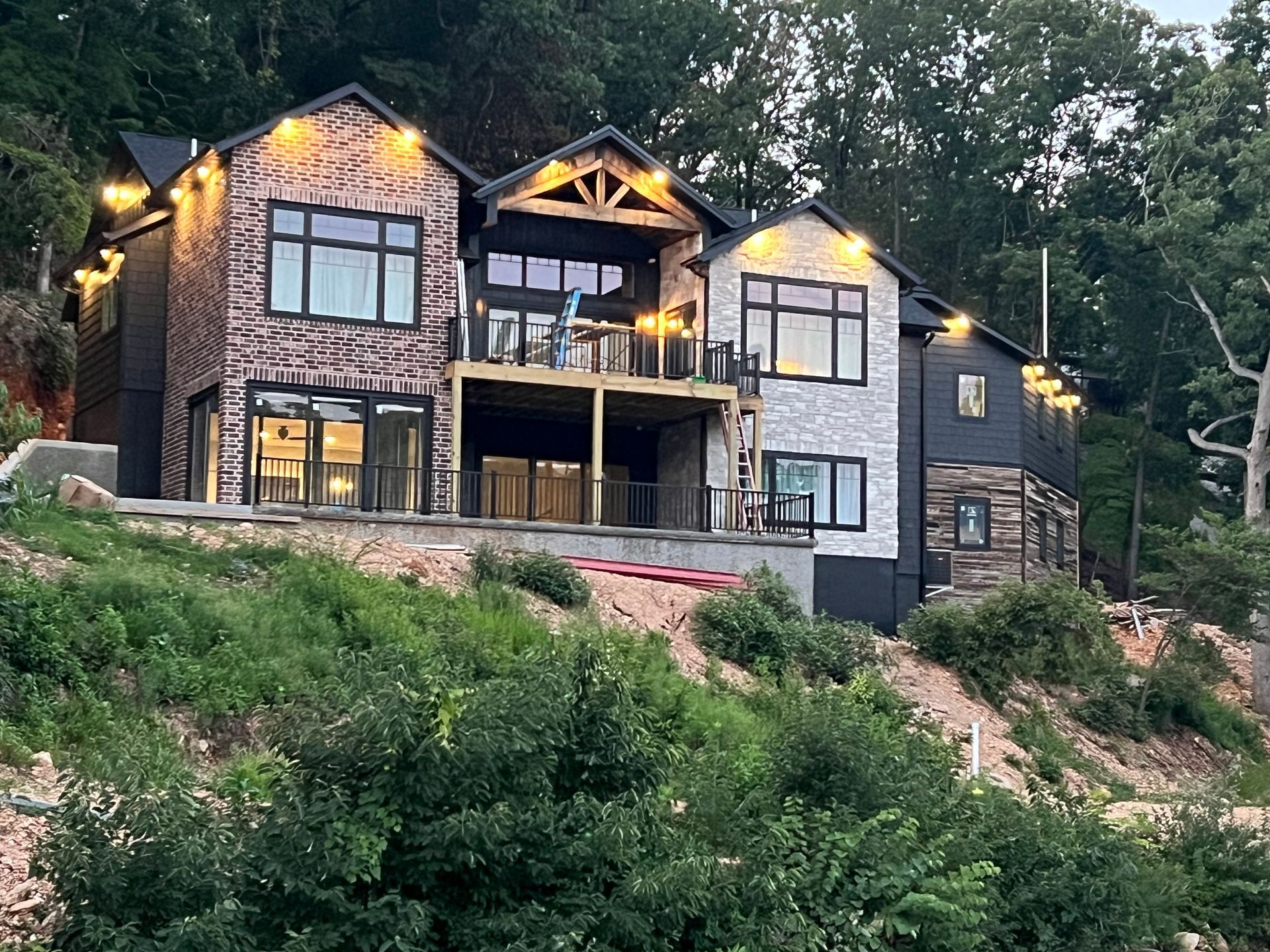 A large house is sitting on top of a hill surrounded by trees.