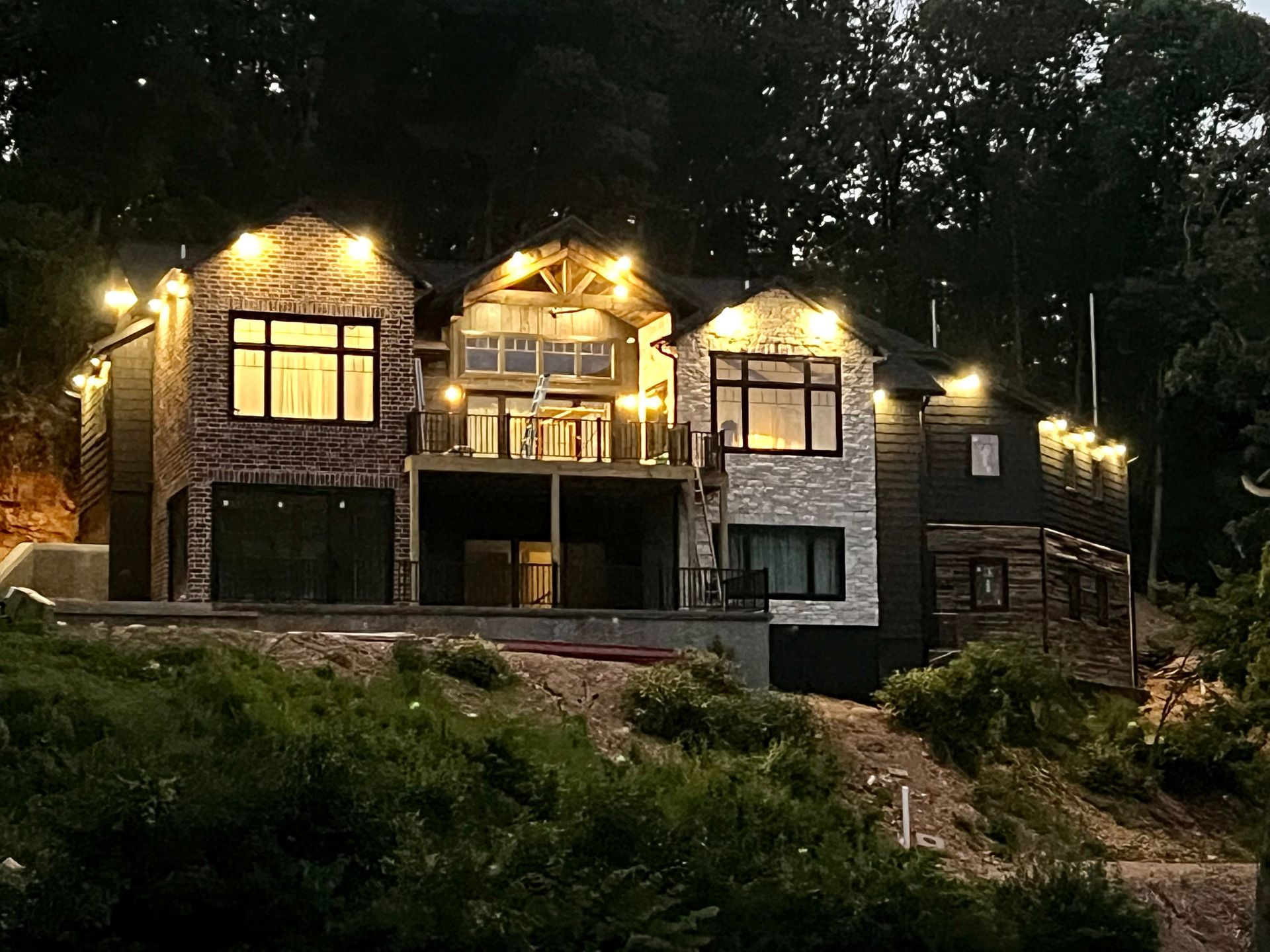 A large house is lit up at night in the middle of a forest.