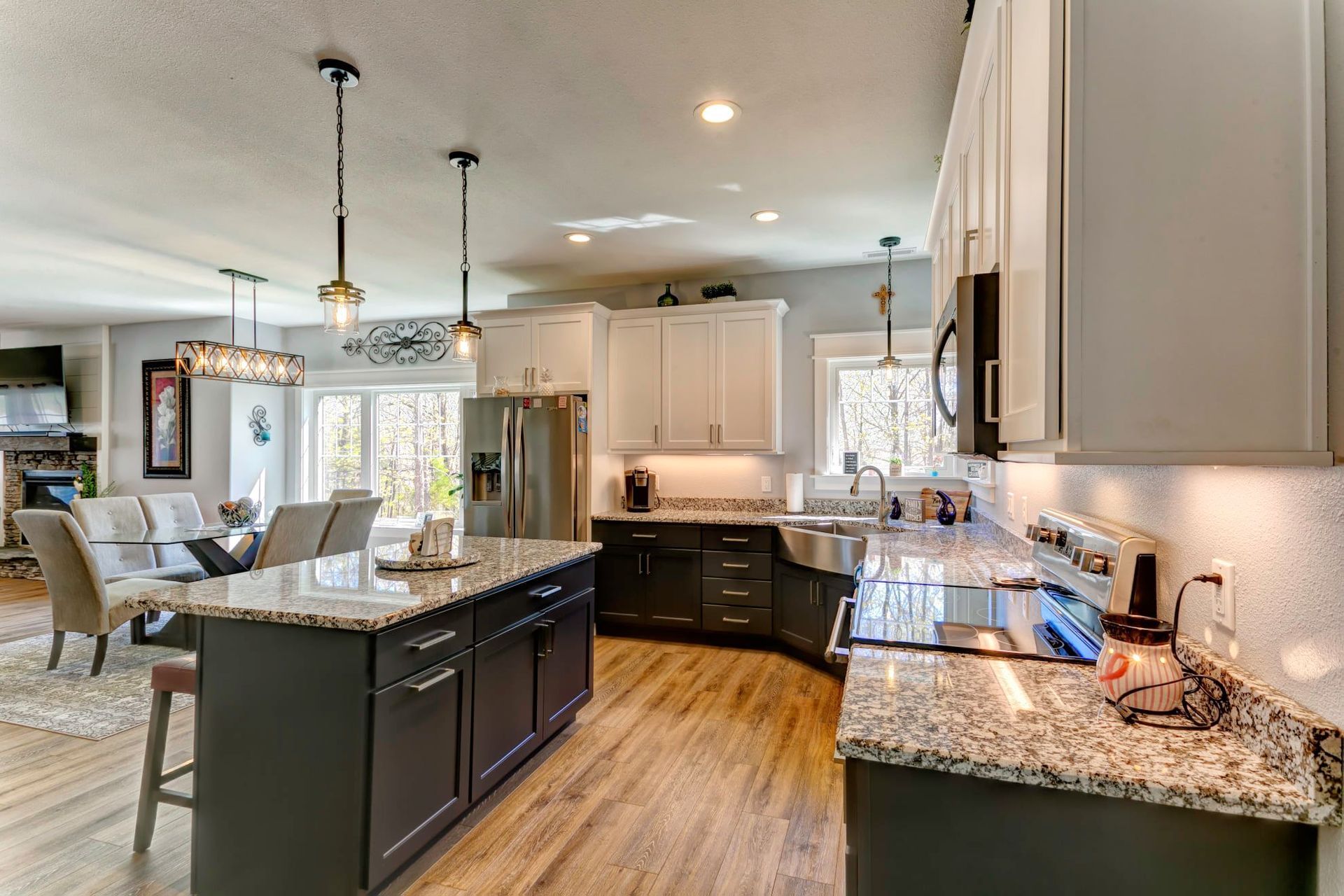 A kitchen with granite counter tops , black cabinets , stainless steel appliances and a large island.