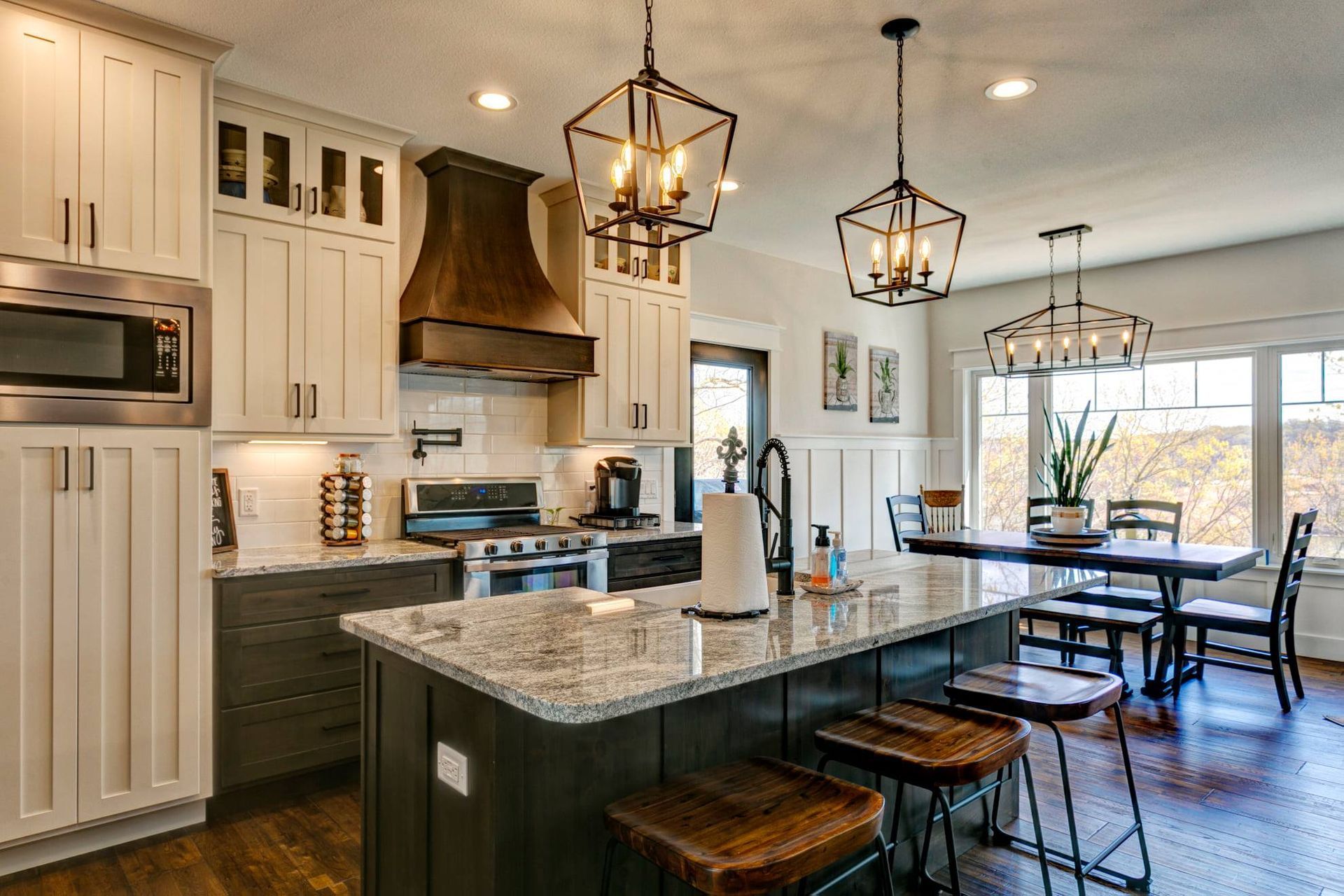 A kitchen with white cabinets , granite counter tops , stainless steel appliances and a large island.