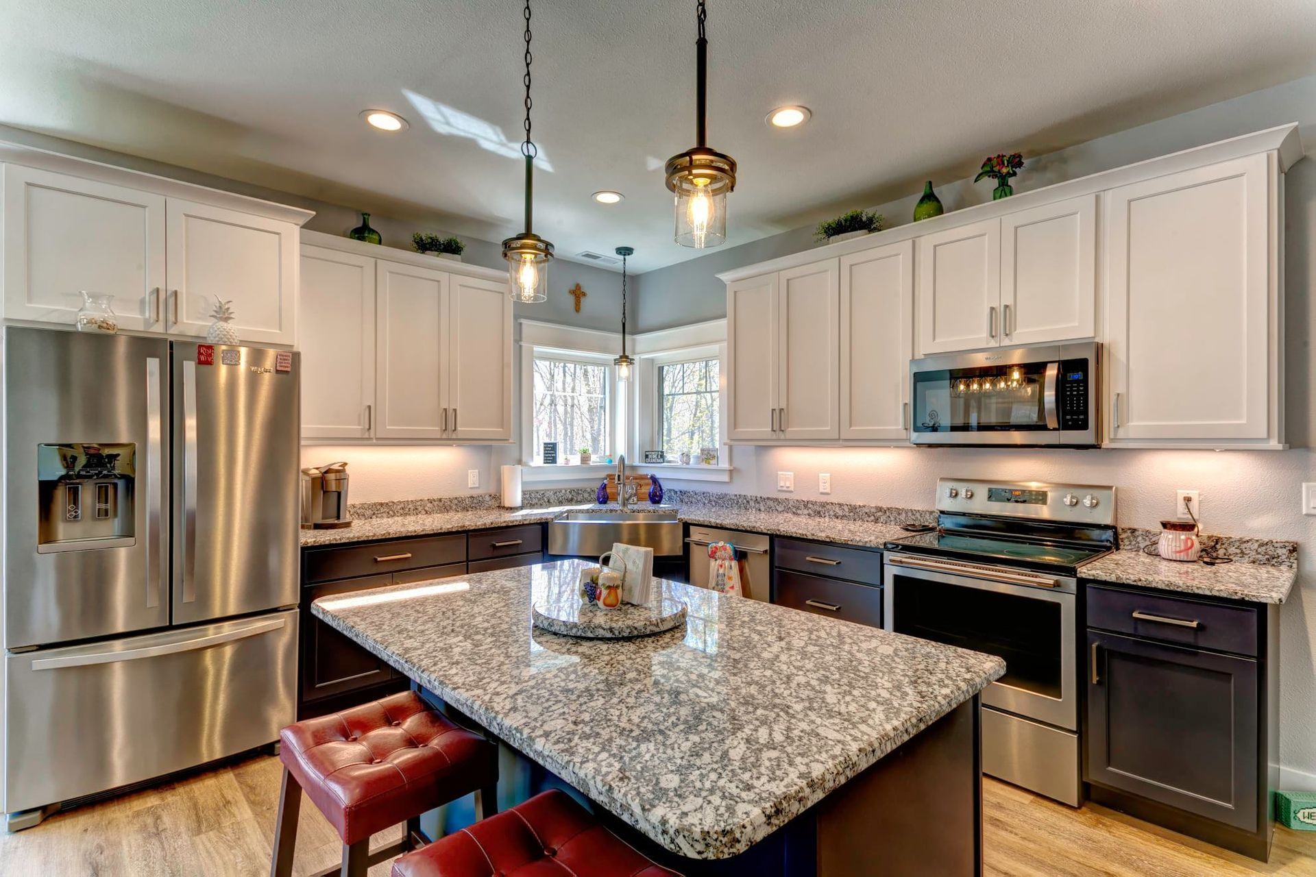 A kitchen with granite counter tops , stainless steel appliances , and white cabinets.