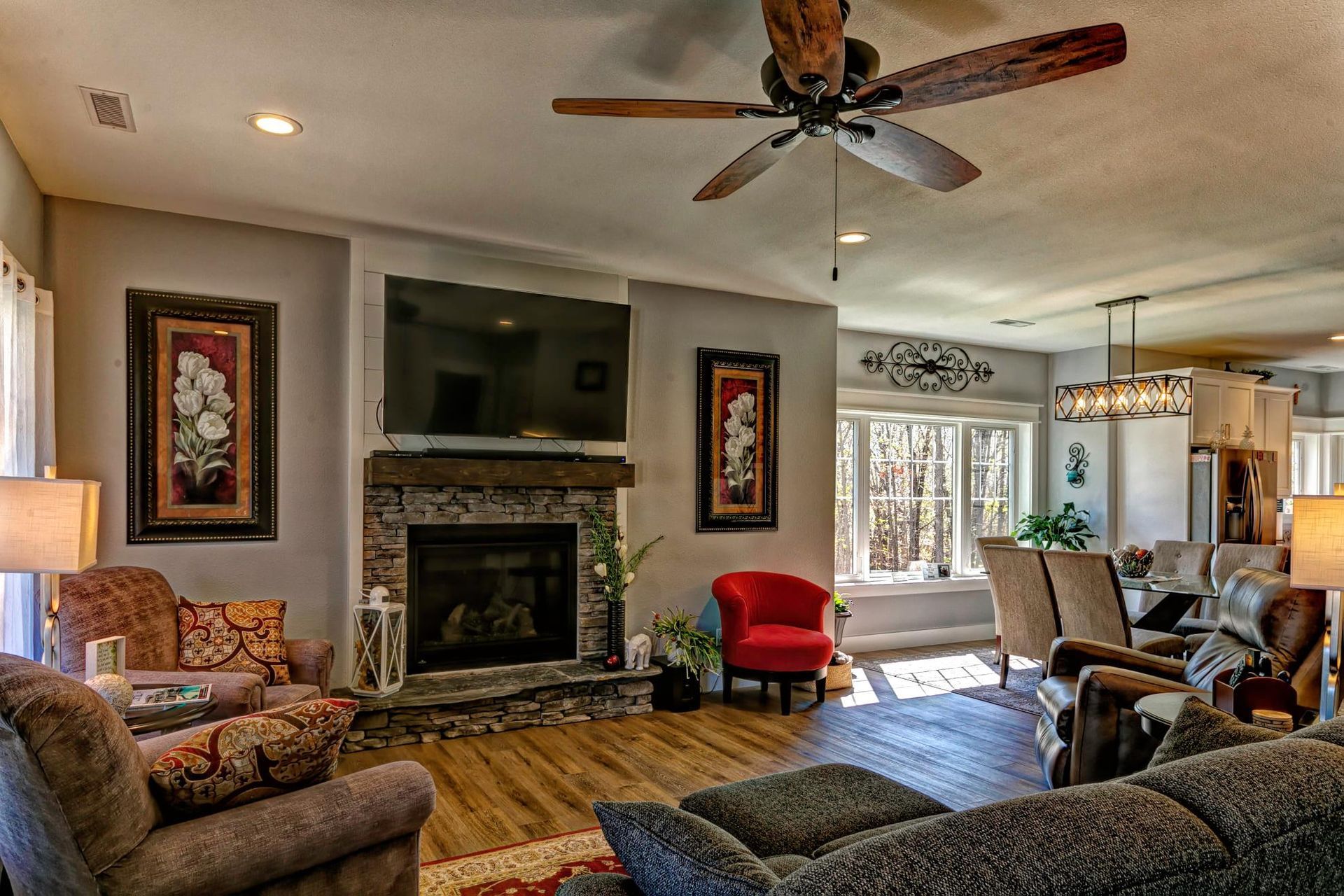 A living room filled with furniture , a fireplace , a flat screen tv and a ceiling fan.