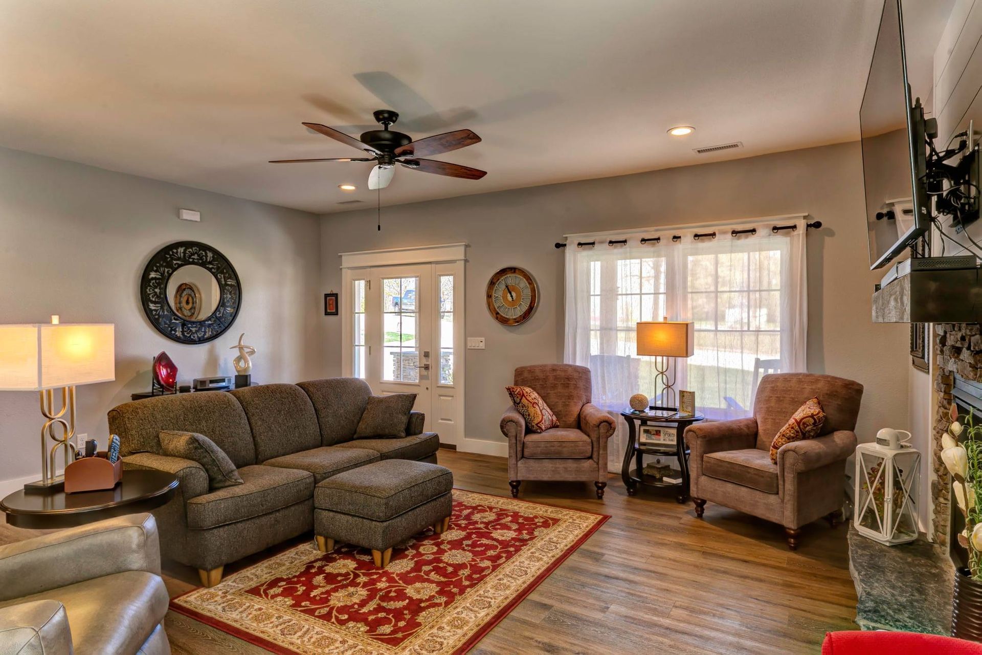 A living room with a couch , chairs , ottoman and a ceiling fan.