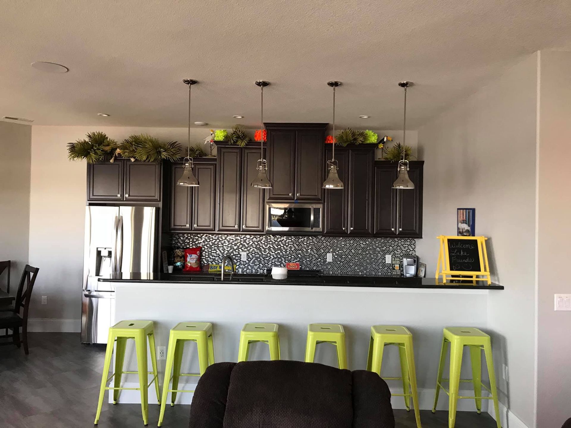 A kitchen with black cabinets and yellow stools