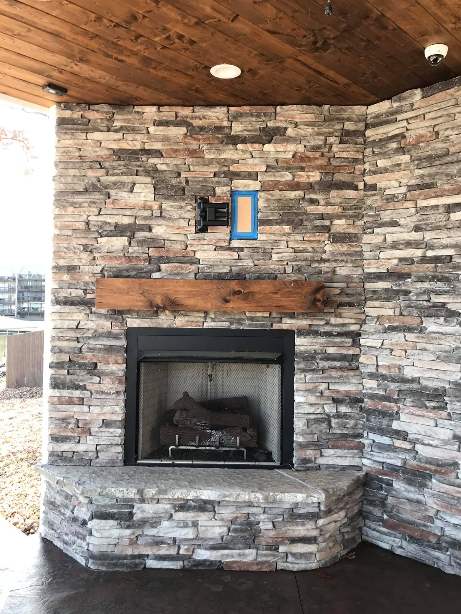 A stone fireplace with a wooden mantle and a wooden ceiling.