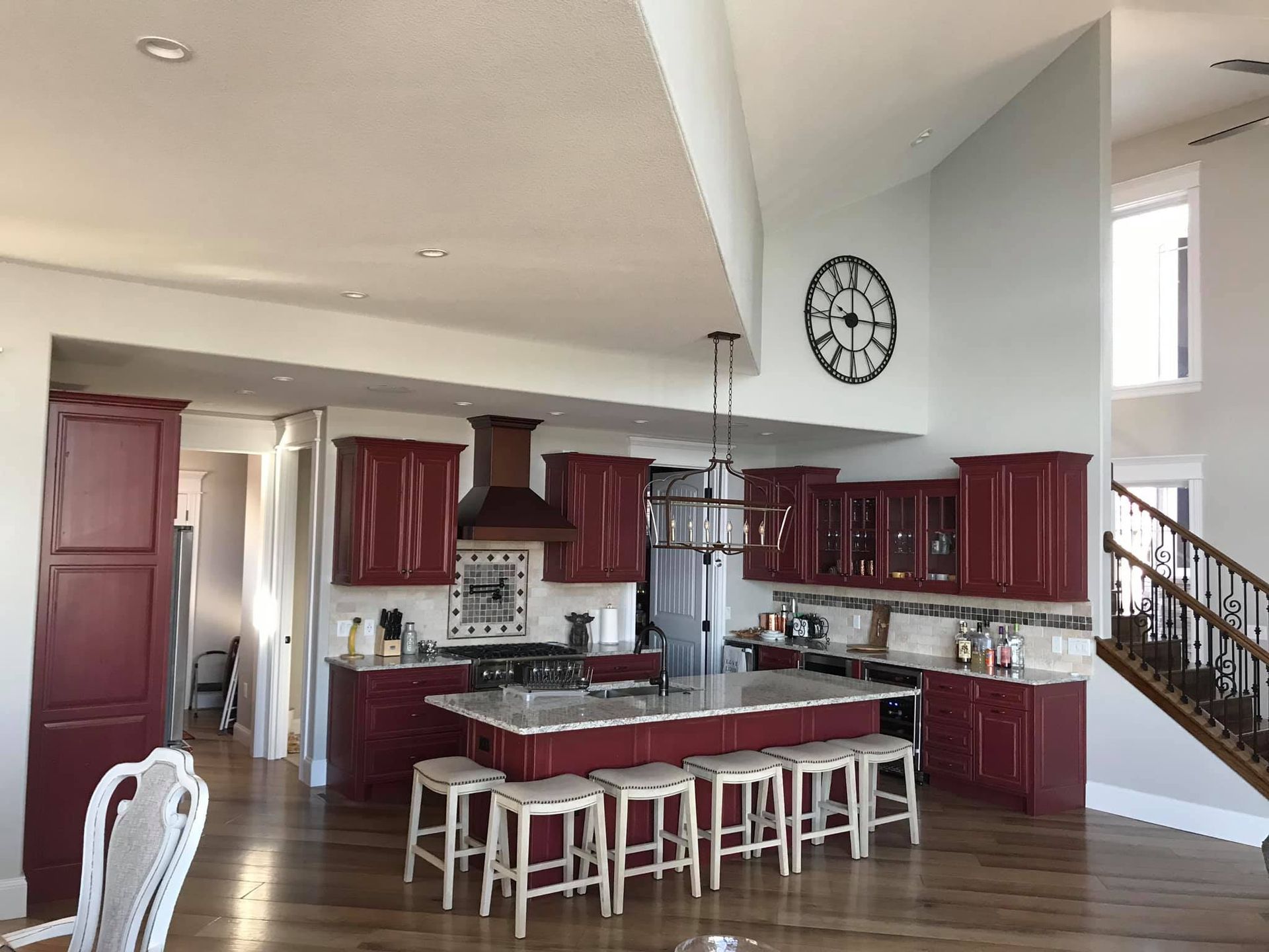 A kitchen with red cabinets and a clock on the wall