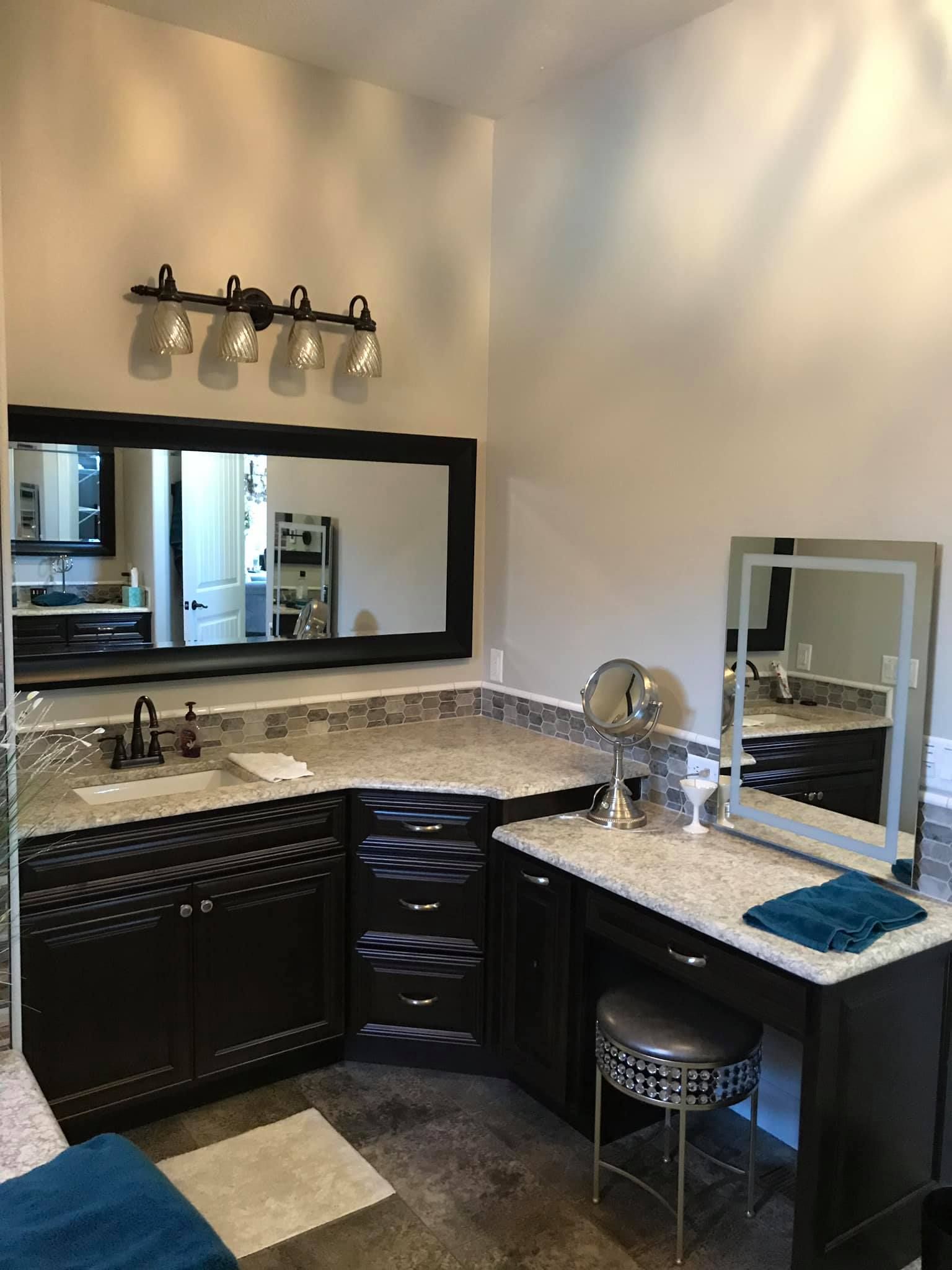A bathroom with two sinks , a vanity , and a large mirror.