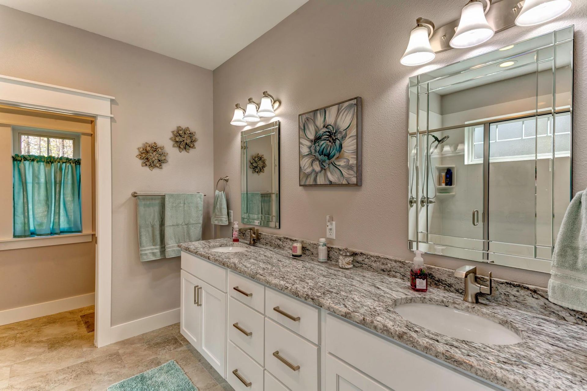 A bathroom with two sinks , a mirror and a window.