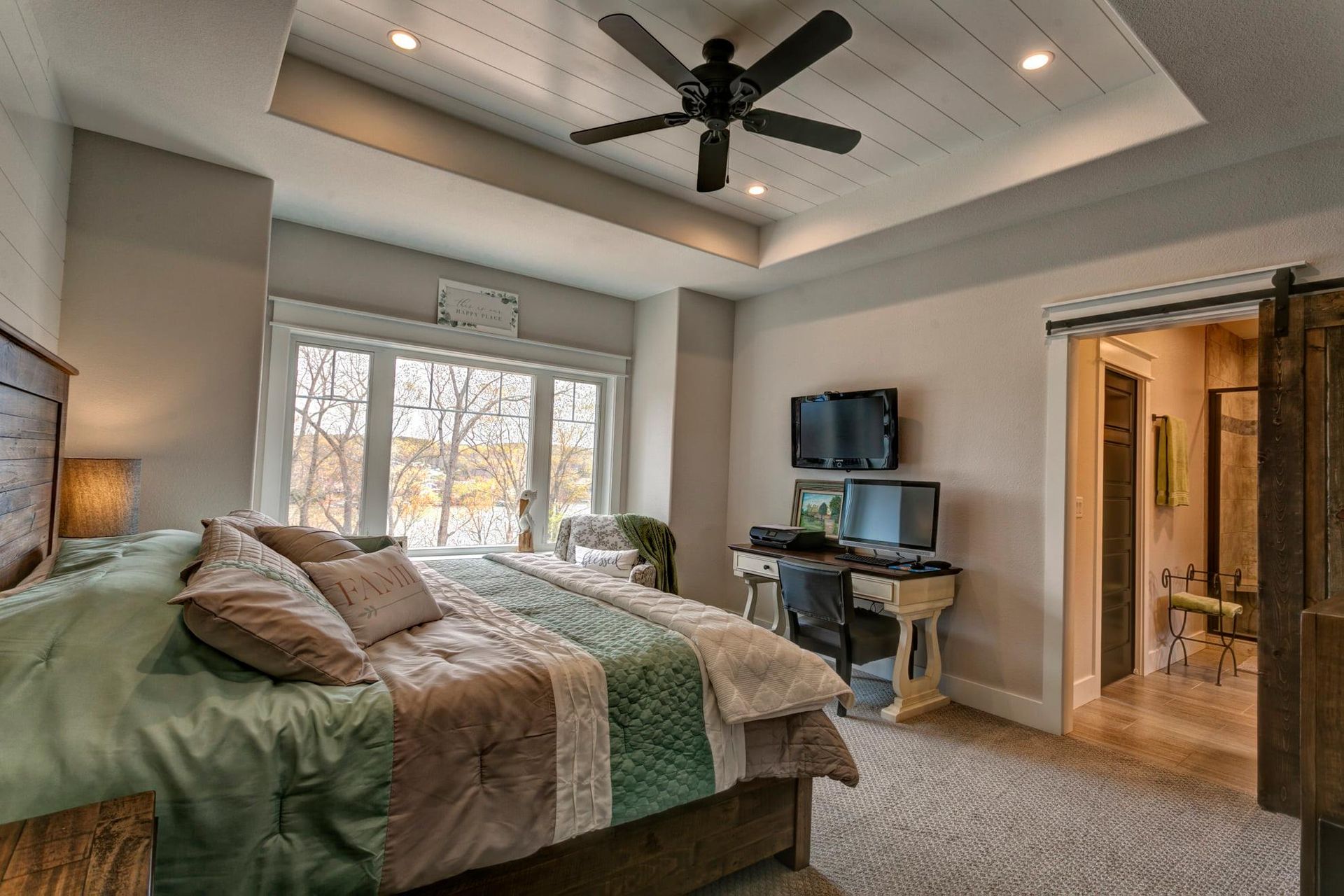 A bedroom with a king size bed and a ceiling fan.