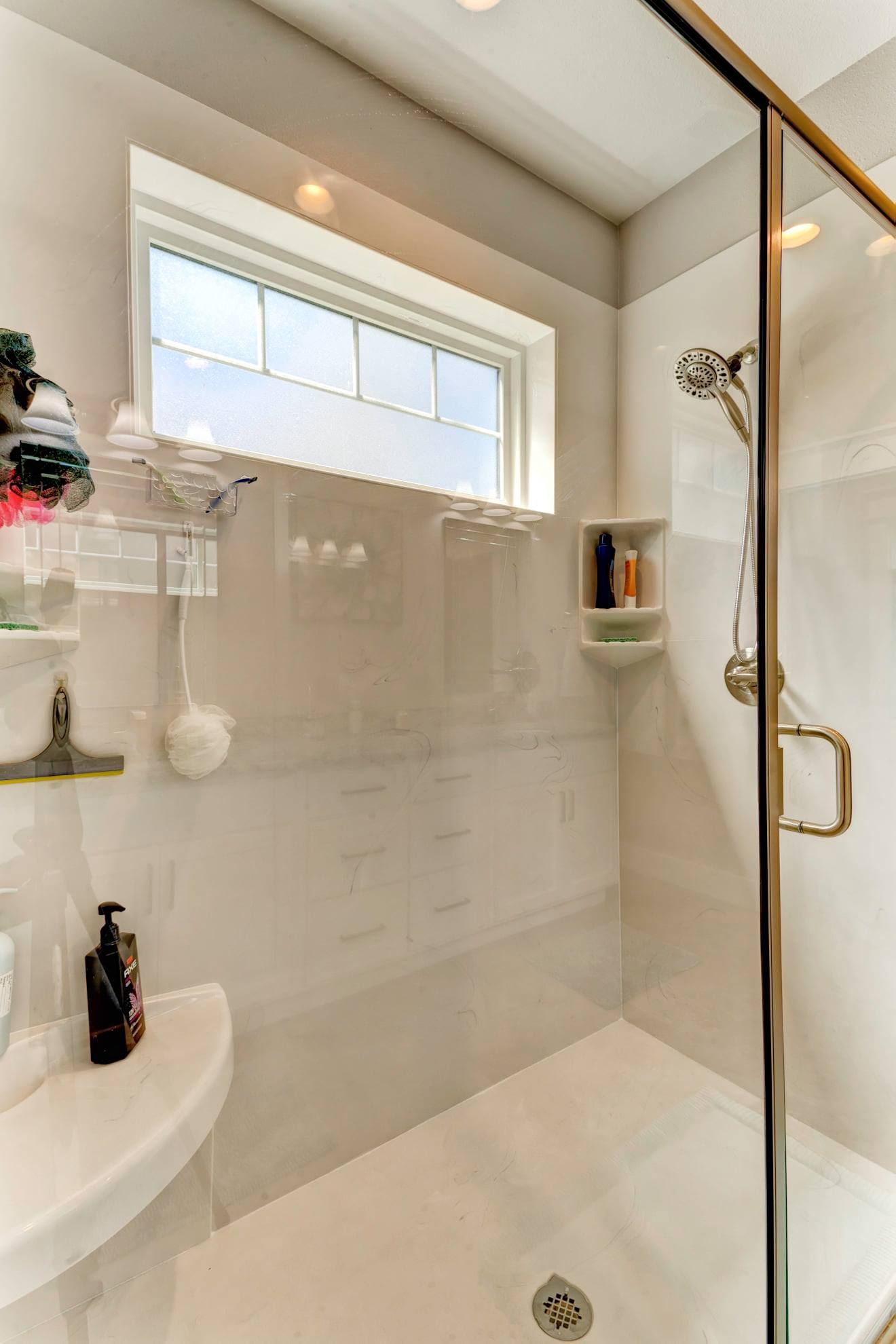 A bathroom with a walk in shower and a window.