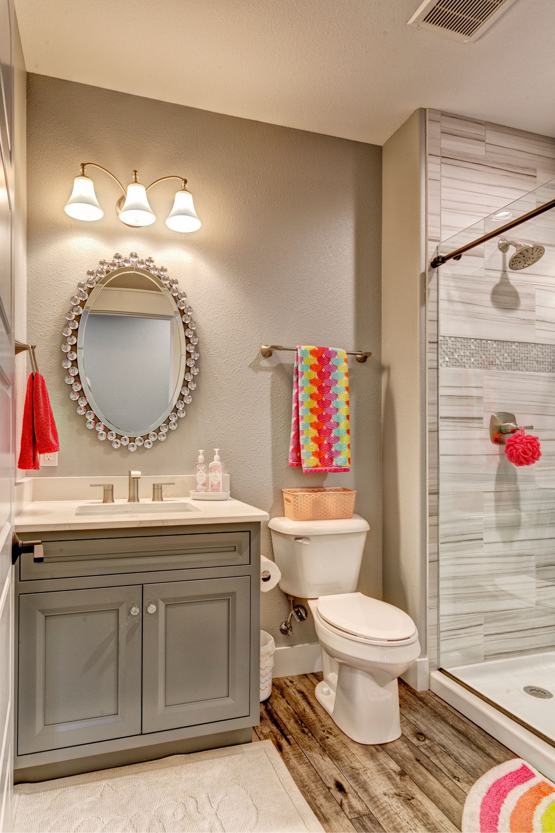 A bathroom with a toilet , sink , mirror and shower.