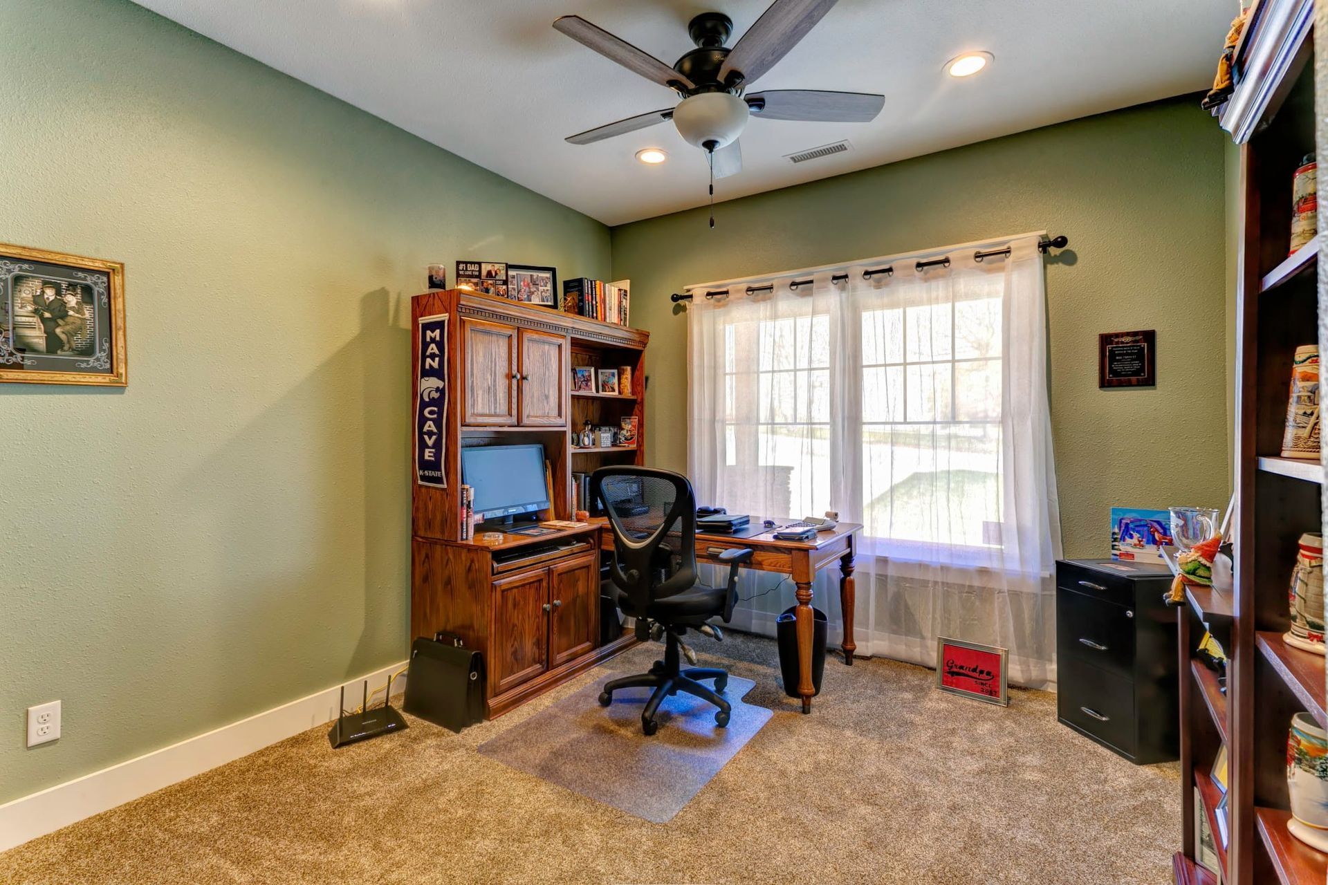 There is a ceiling fan in the room with a desk and chair.