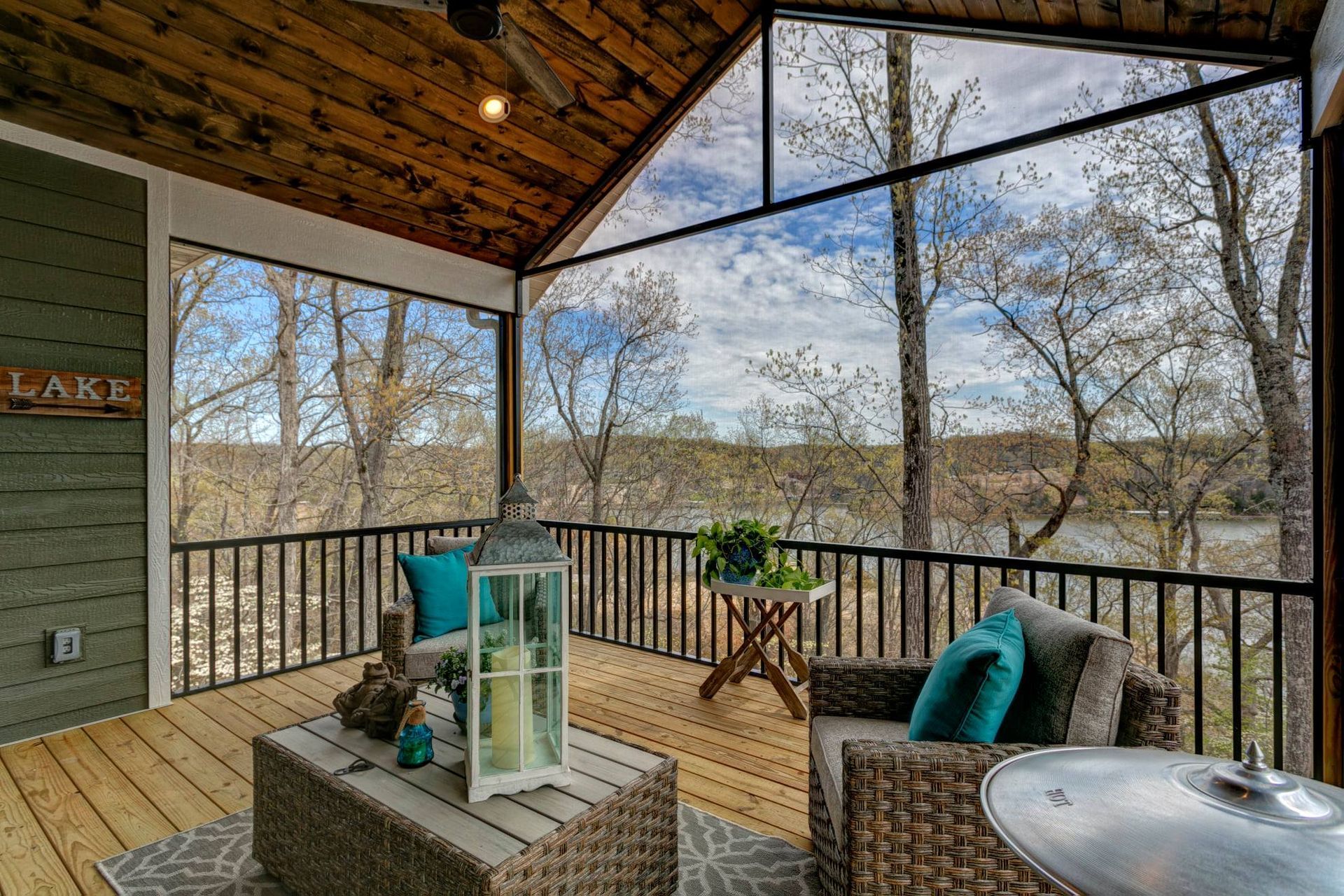 A screened in porch with a view of a lake and trees.
