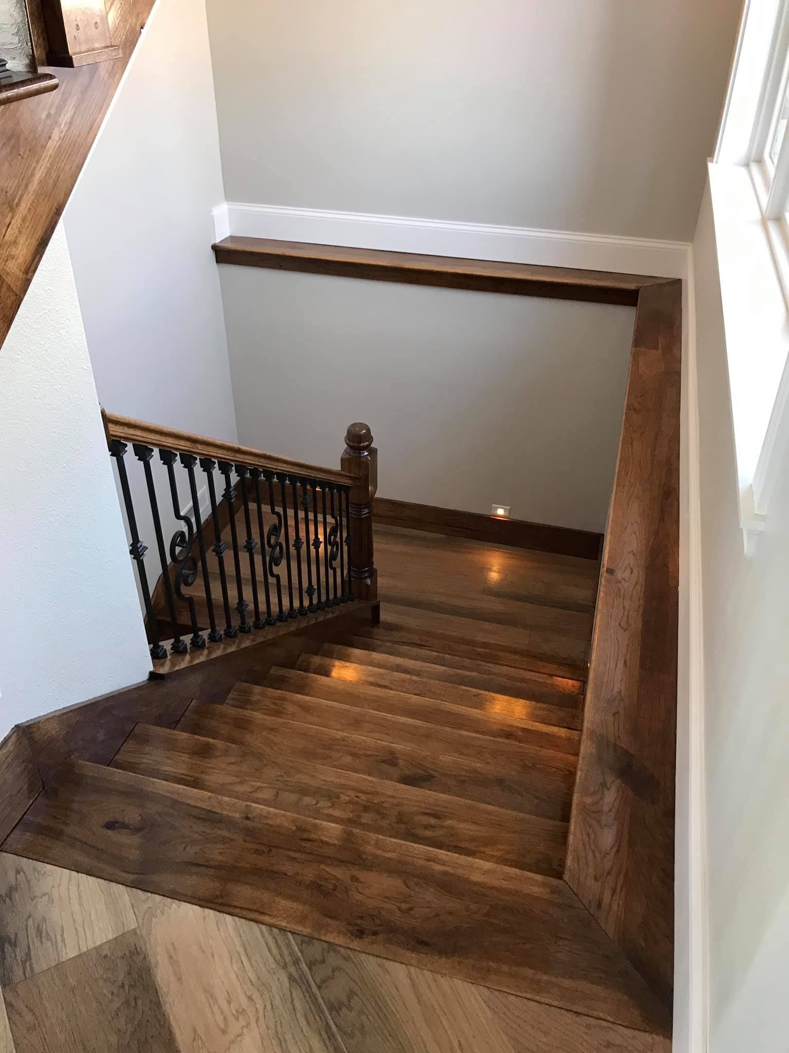 A wooden staircase with a wrought iron railing in a house.