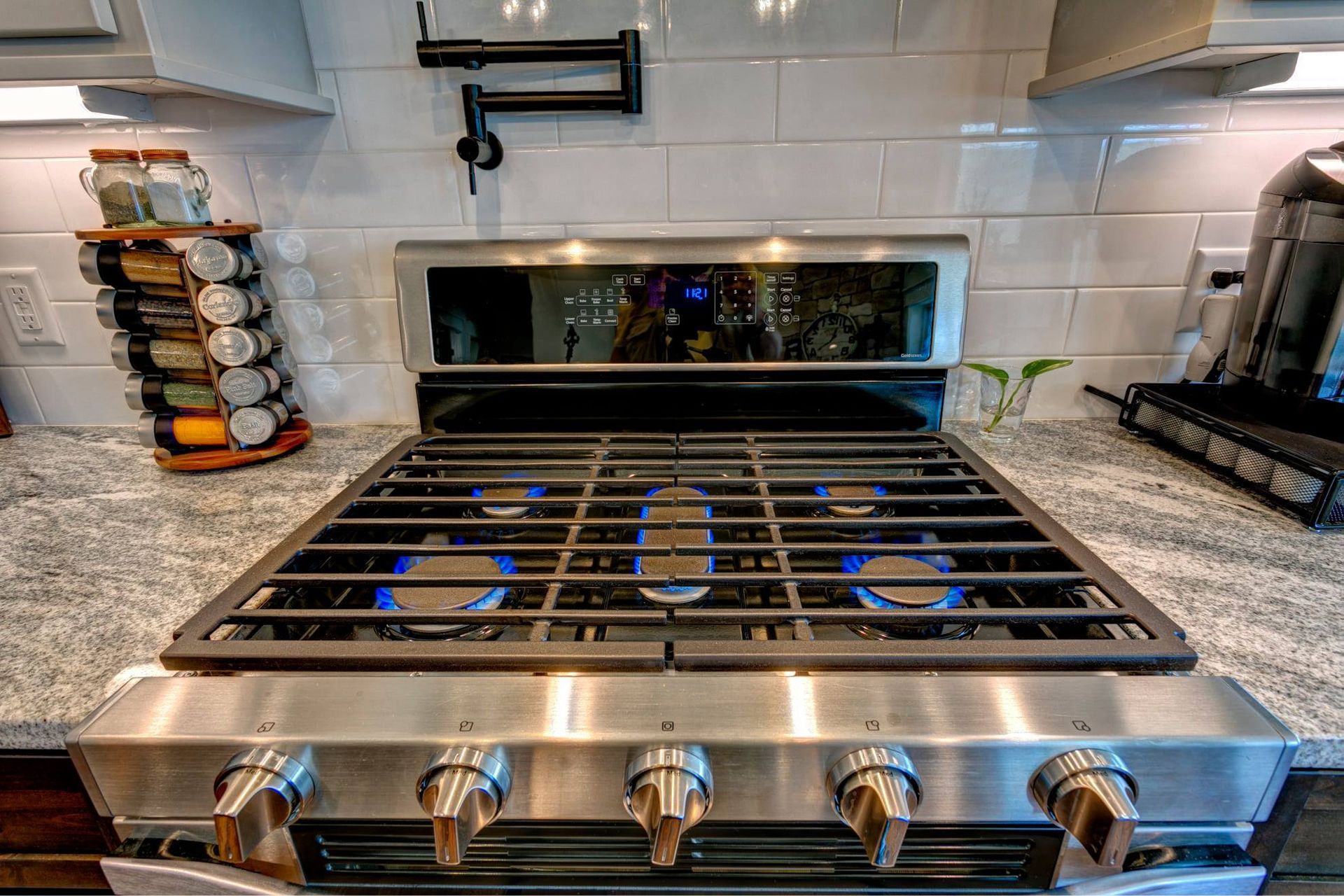 A stainless steel stove top oven is sitting on top of a granite counter in a kitchen.