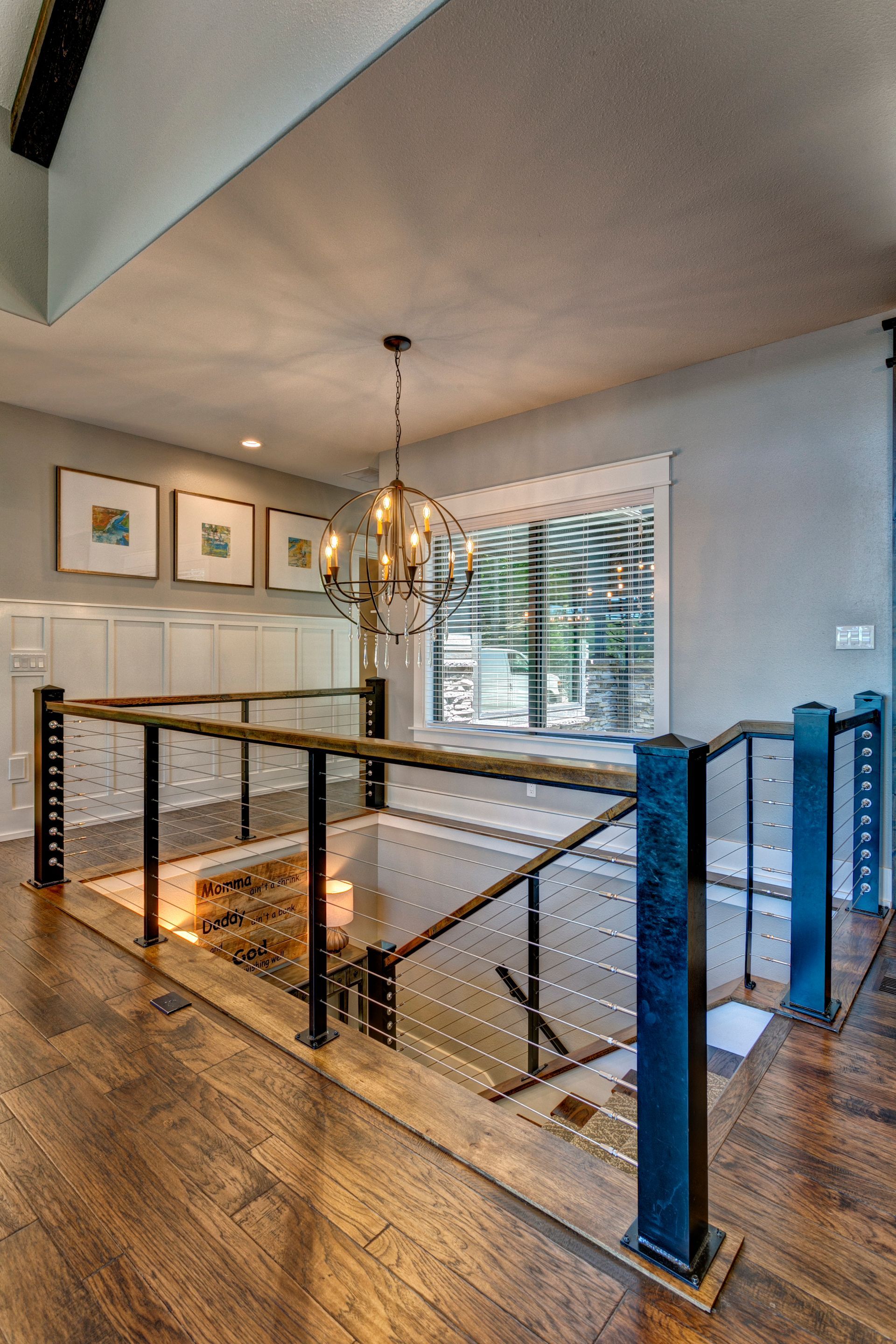 A staircase with a glass railing and a chandelier hanging from the ceiling.