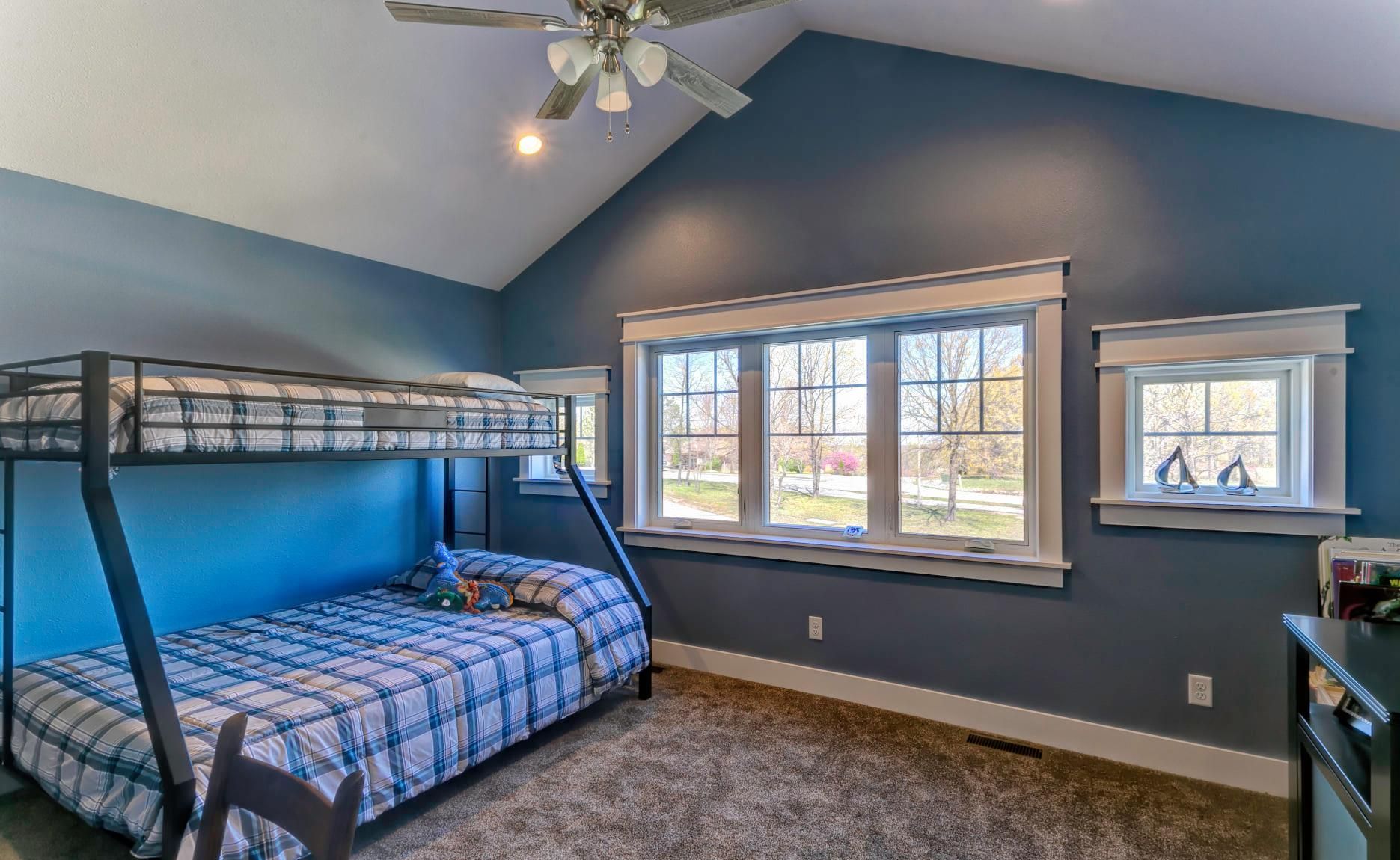 A bedroom with a bunk bed and a ceiling fan.