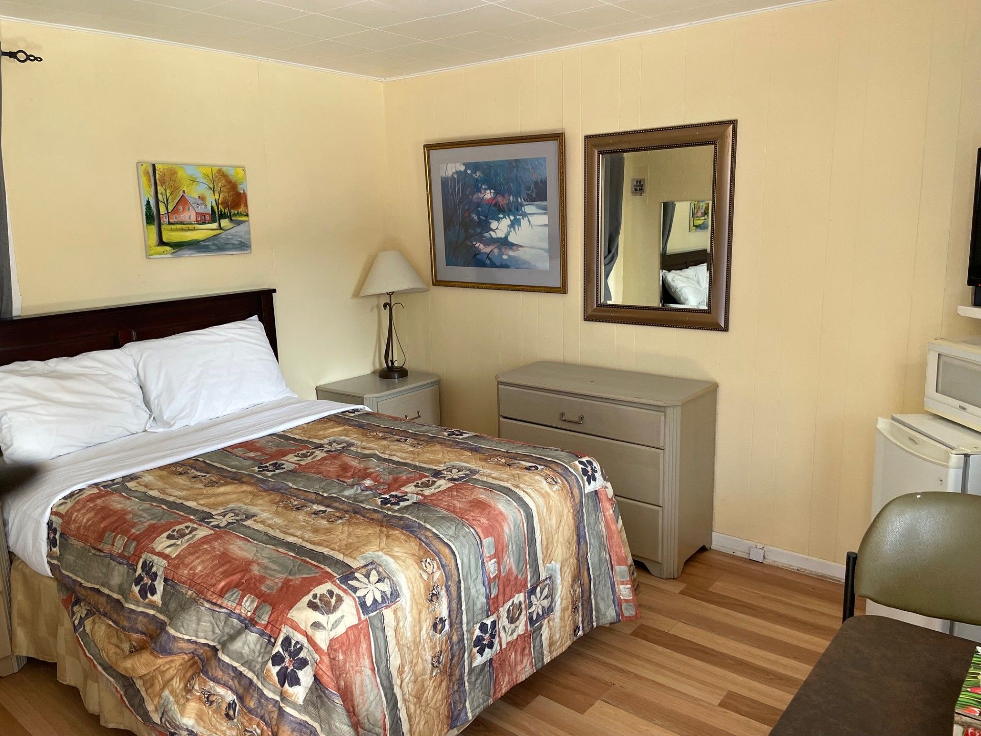 Une chambre d'hôtel avec un lit, une commode, un miroir et un micro-ondes.