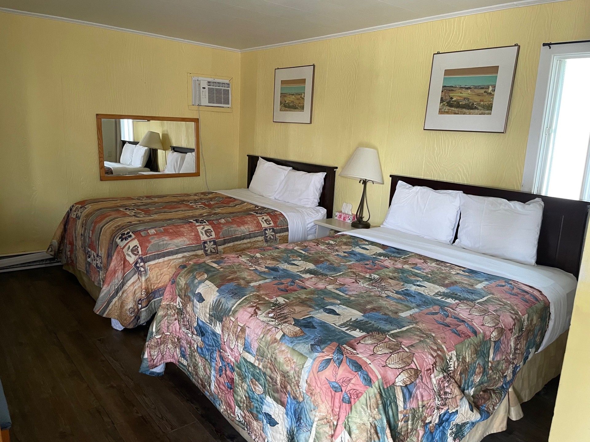 Une chambre d'hôtel avec deux lits et un miroir.