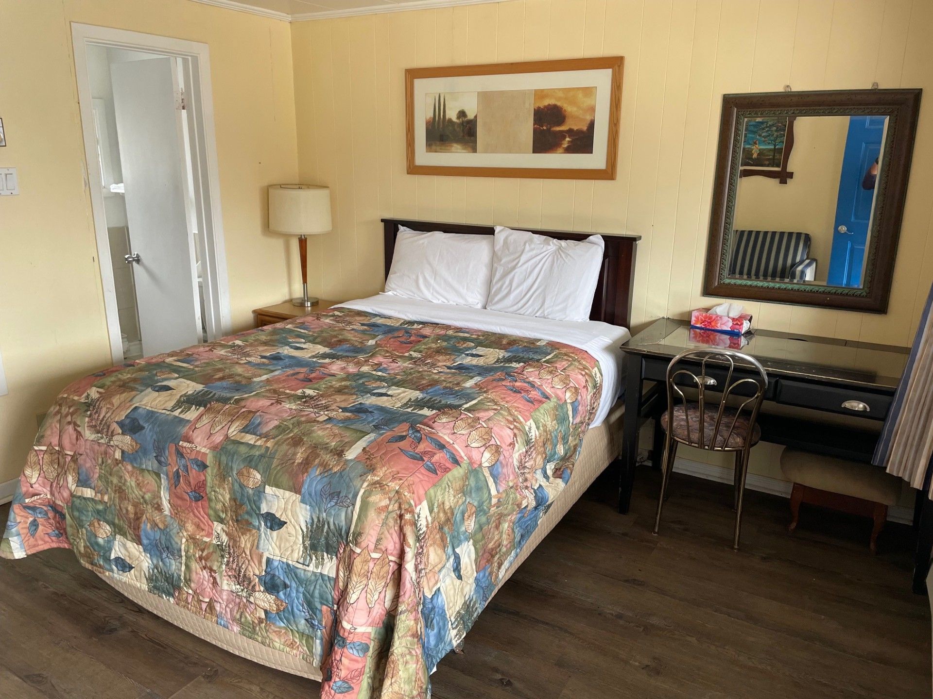 Une chambre d'hôtel avec un lit, un bureau, une chaise et un miroir.