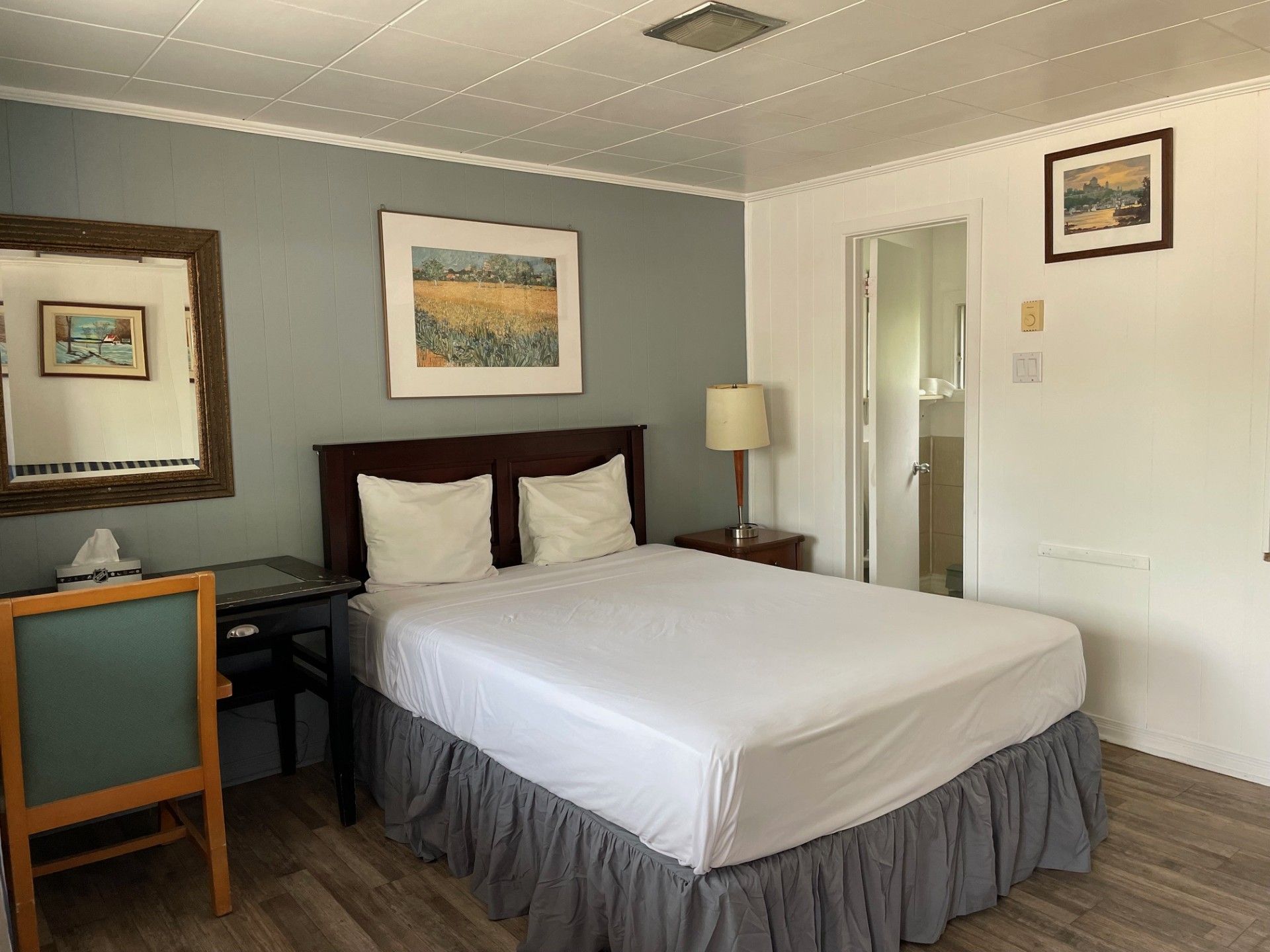 Une chambre d'hôtel avec un lit, un bureau, une chaise et un miroir.