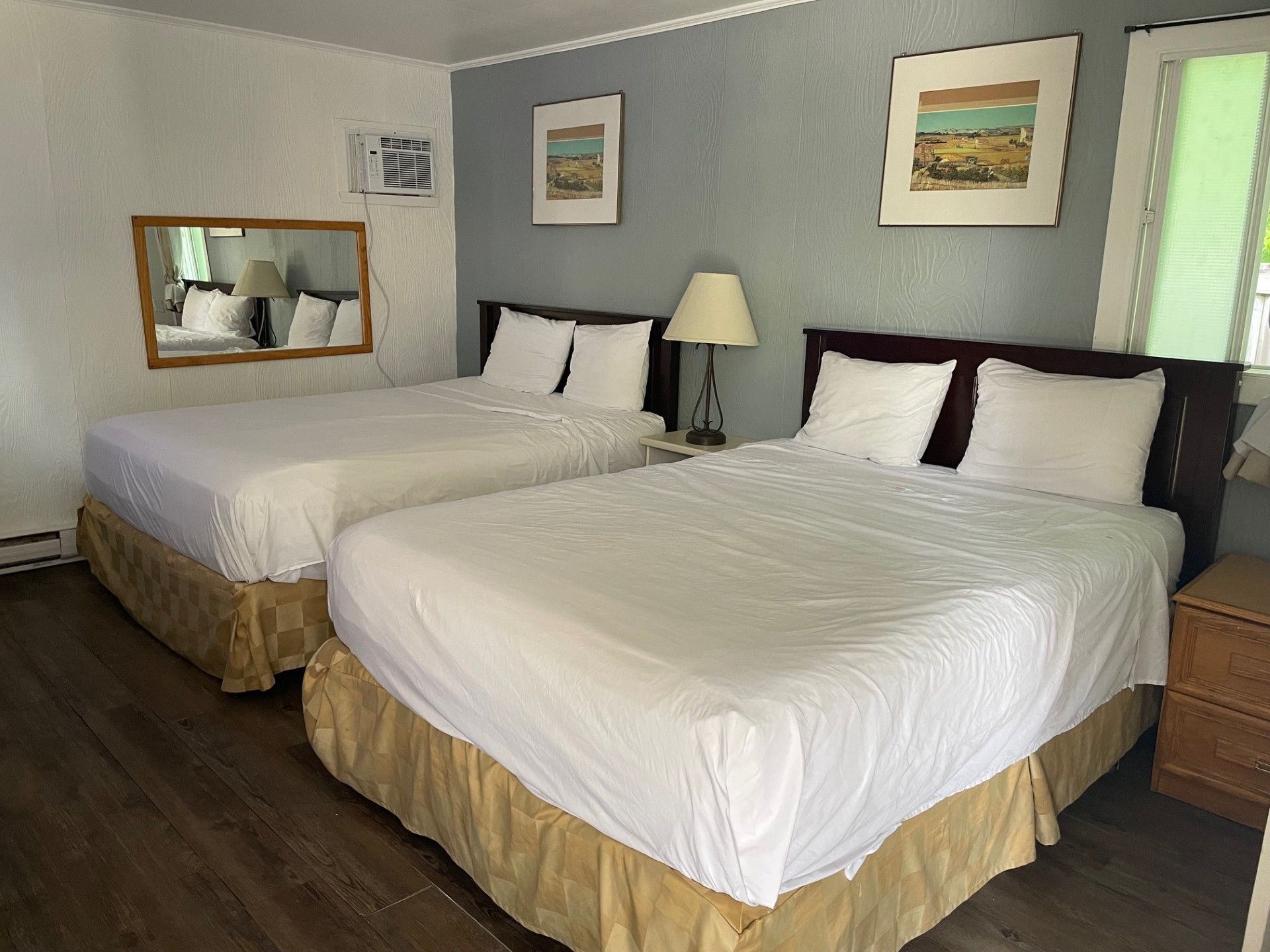 Une chambre d'hôtel avec deux lits et un miroir sur le mur.