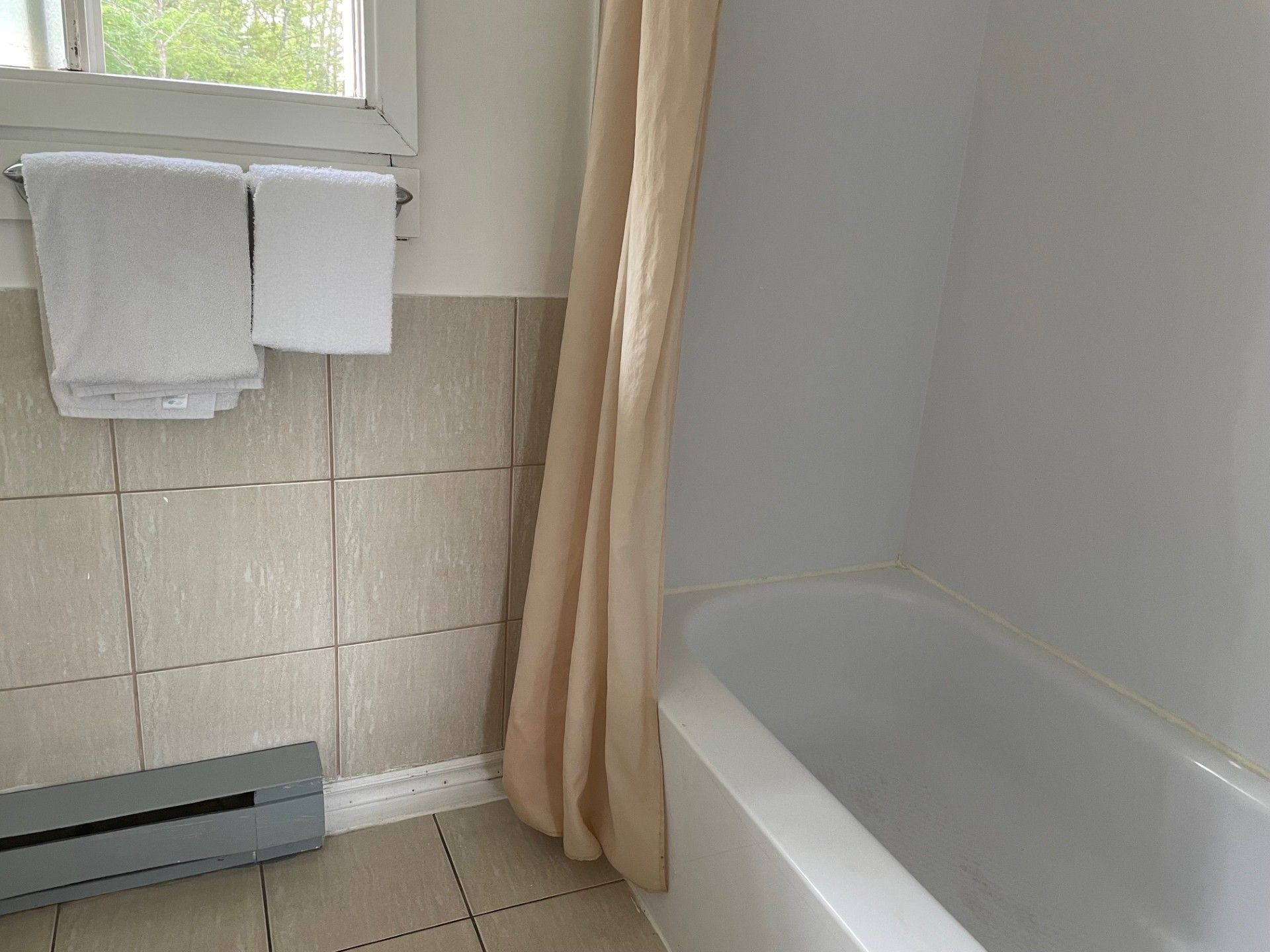 Une salle de bain avec une baignoire et deux serviettes accrochées au mur