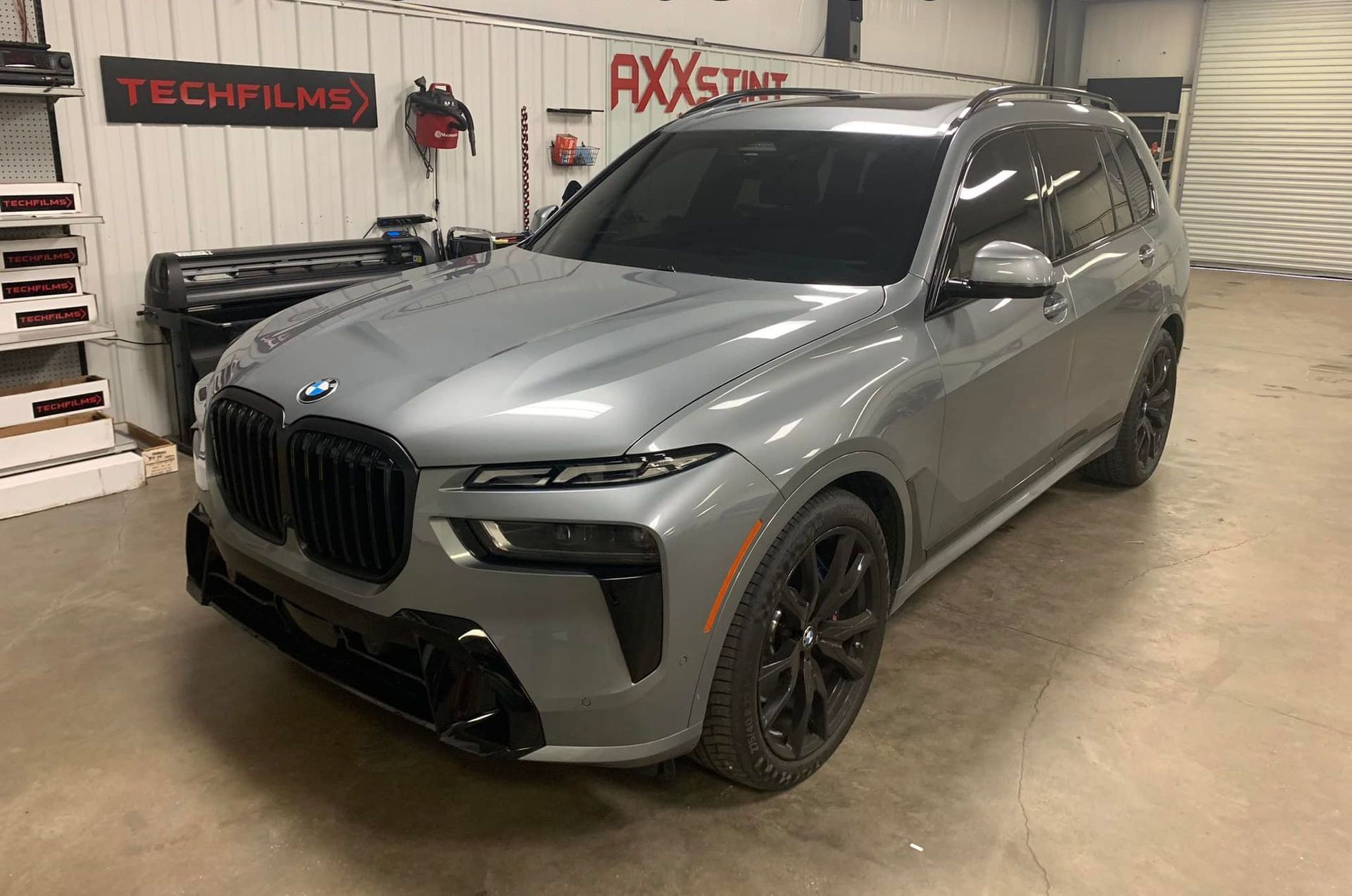 A gray bmw x7 is parked in a garage.