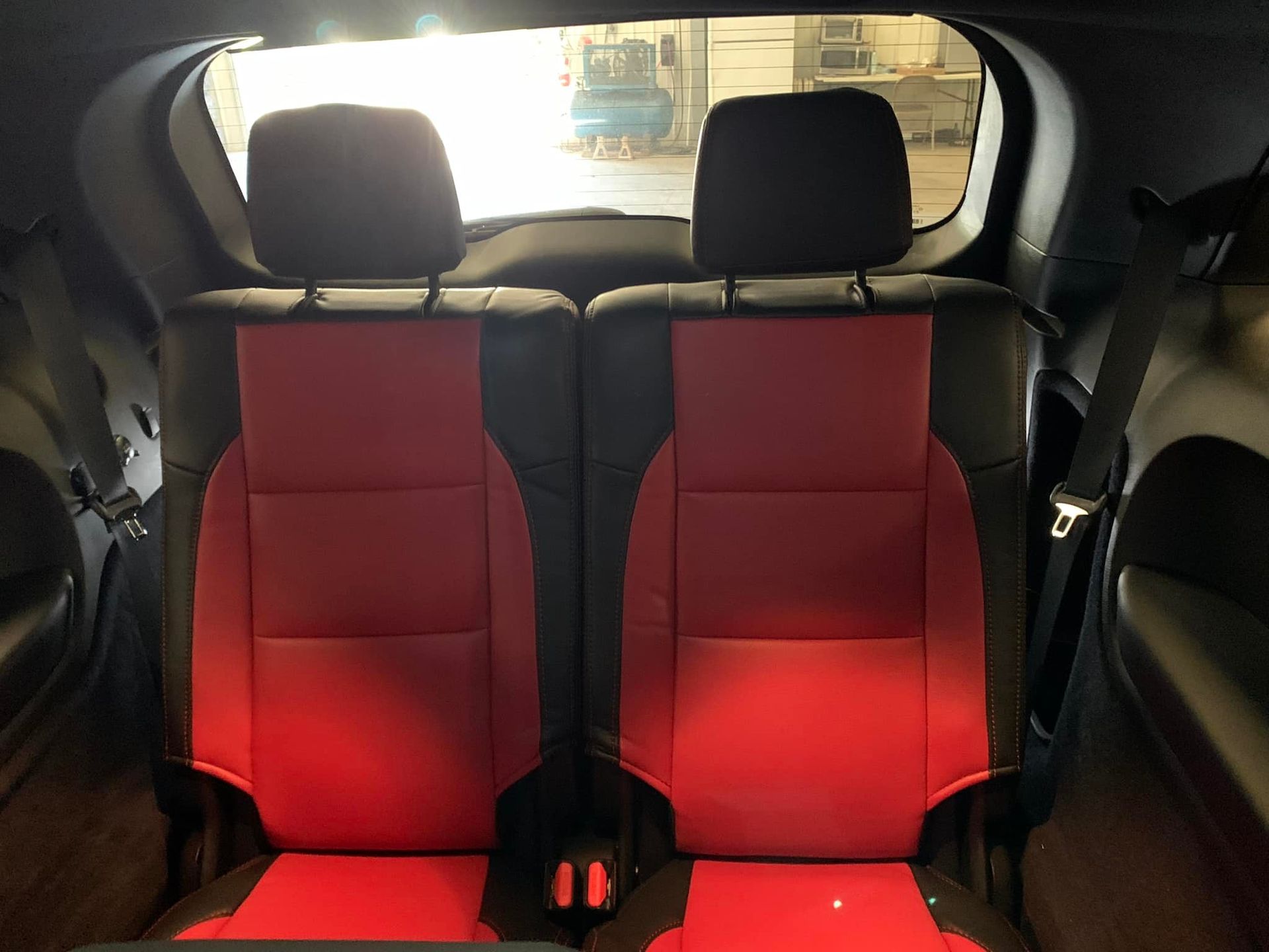 The back seat of a car with red and black seats