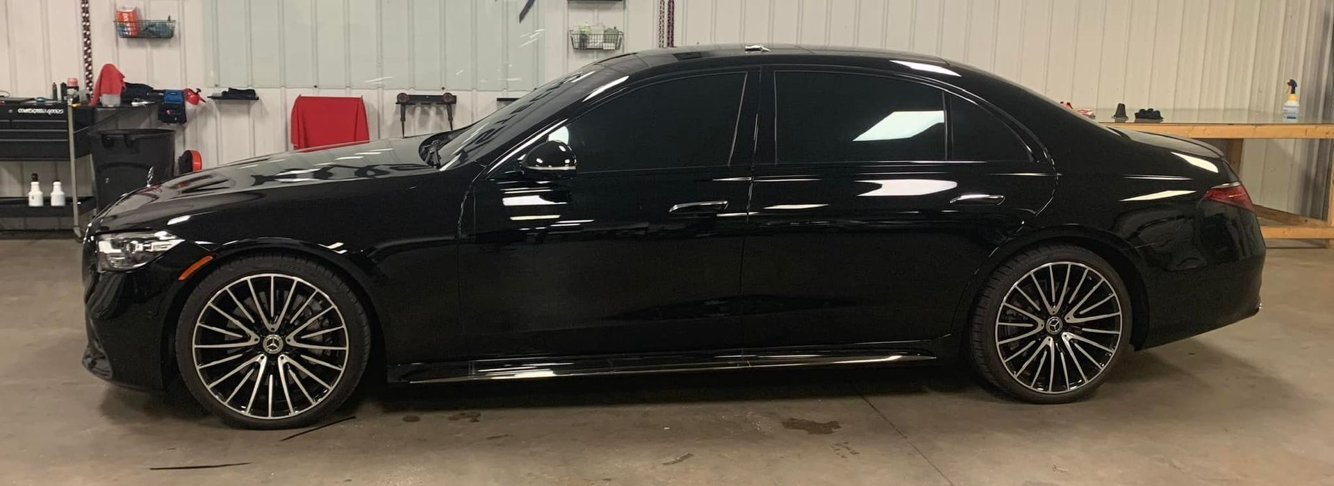 A black mercedes benz is parked in a garage.