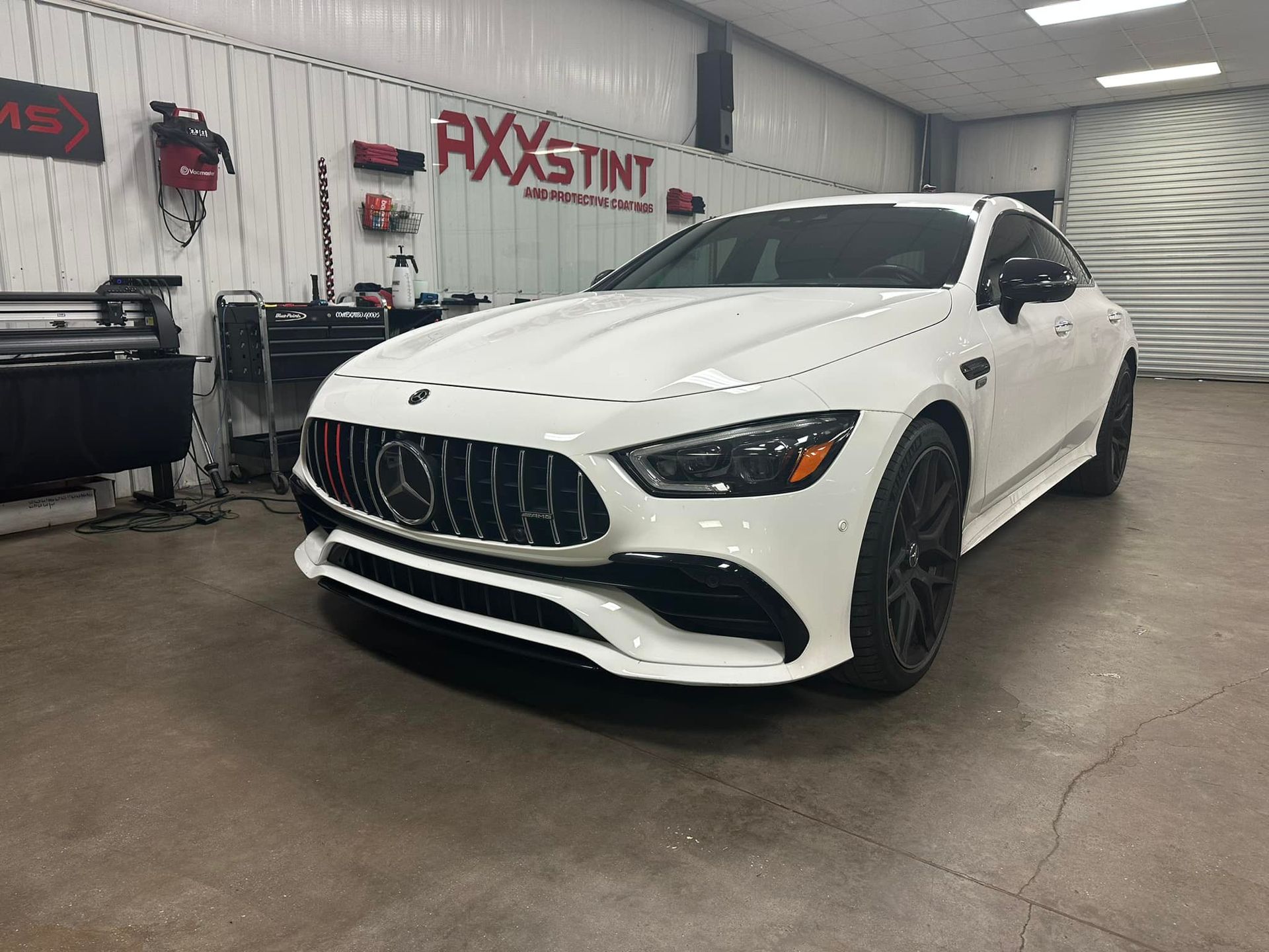 A white mercedes amg gt 63 s is parked in a garage.