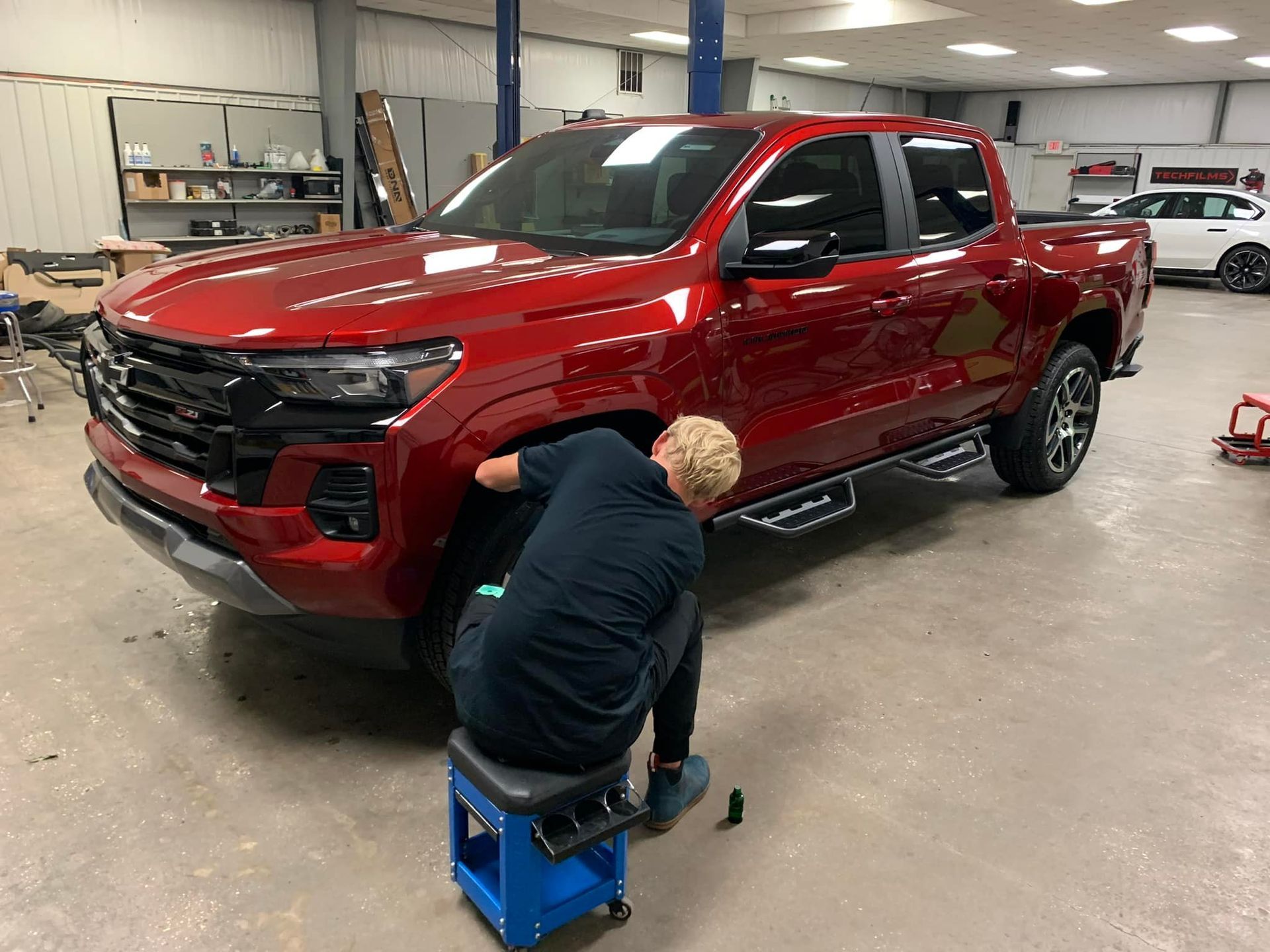 A man is working on a red truck in a garage.