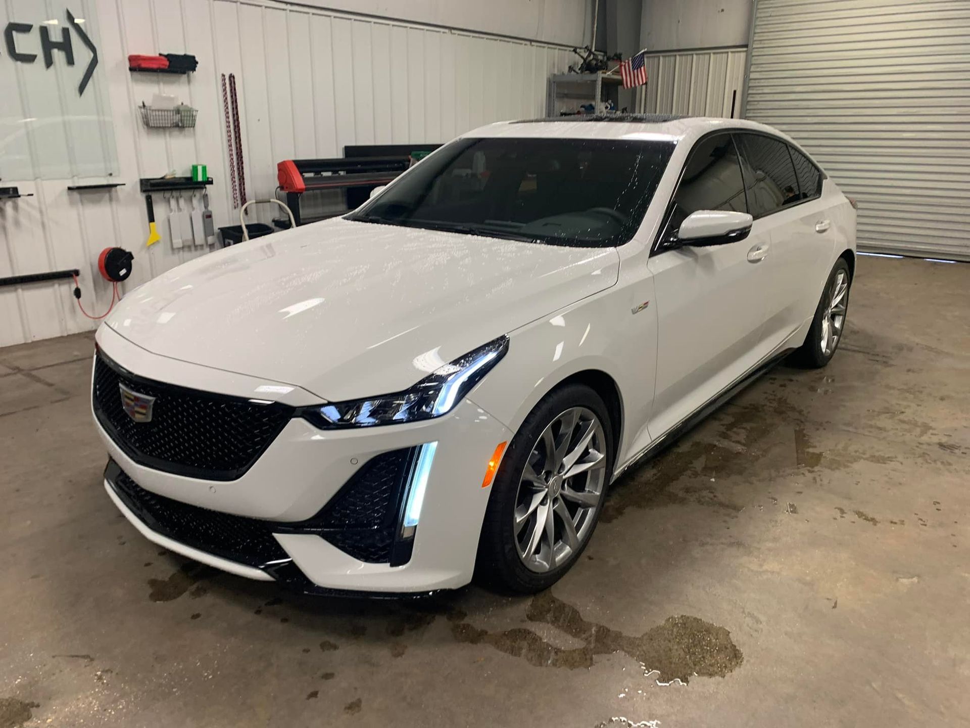 A white cadillac is parked in a garage.