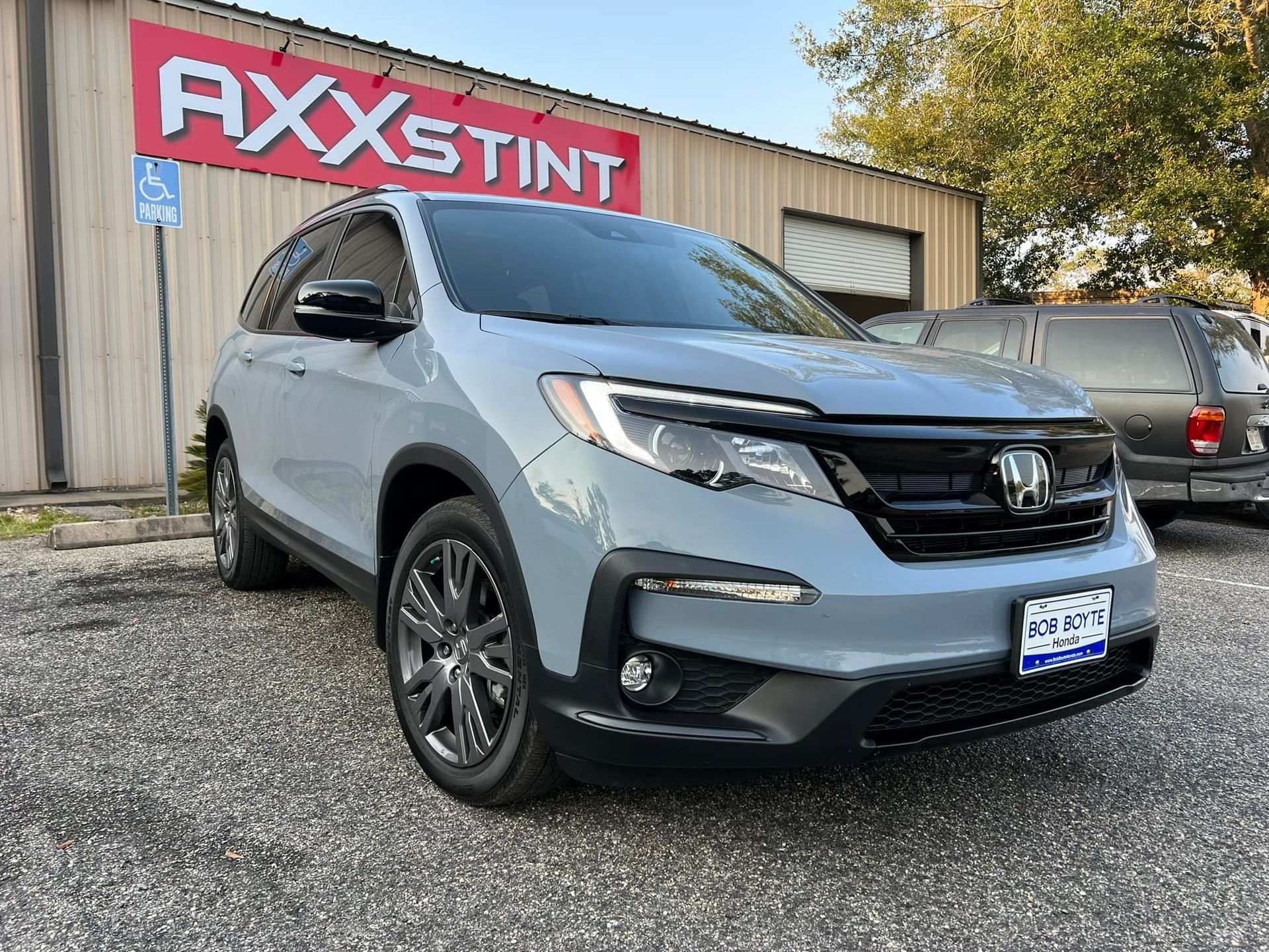 A gray honda ridgeline is parked in front of a building.