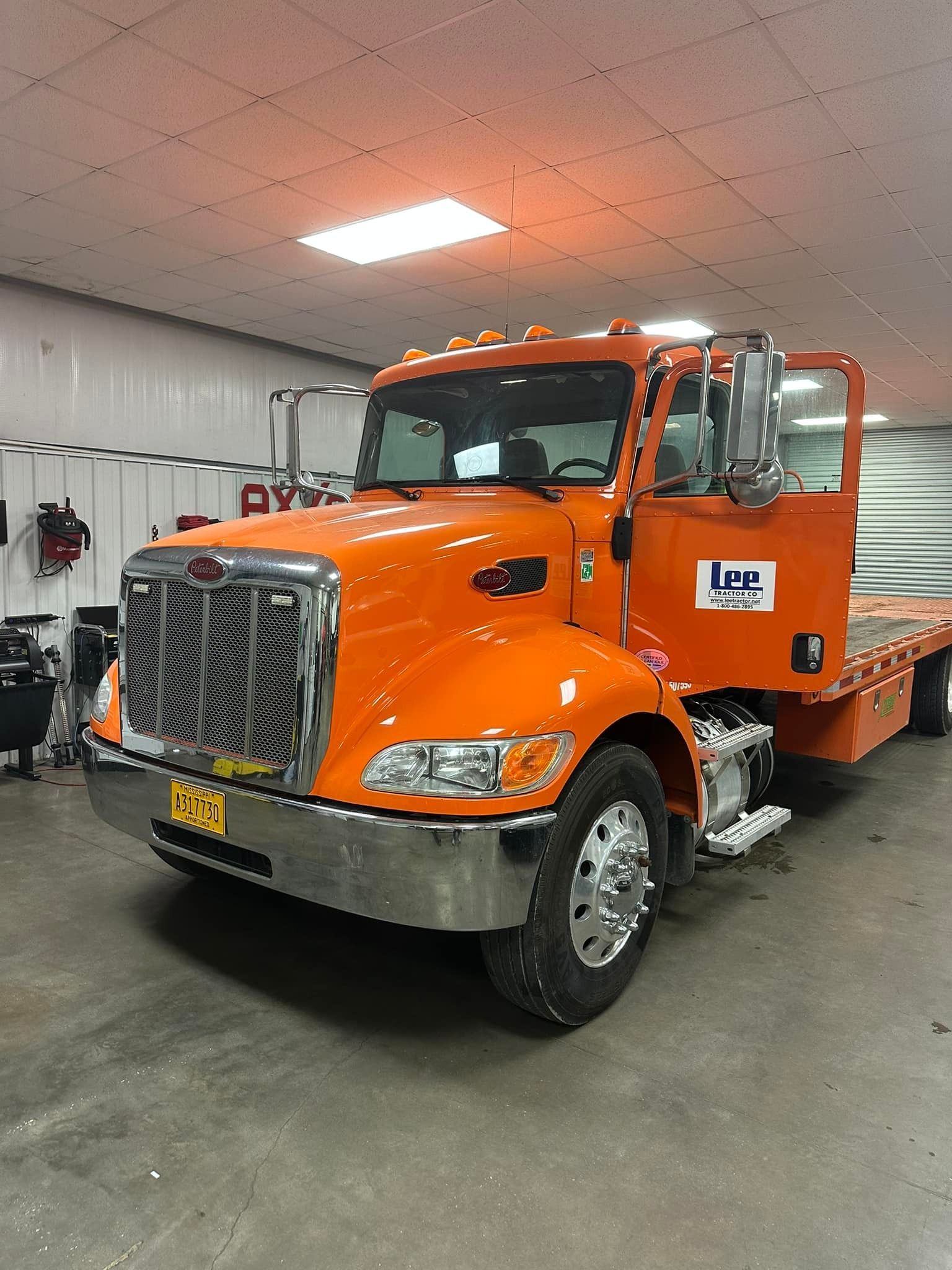 An orange flatbed truck is parked in a garage.