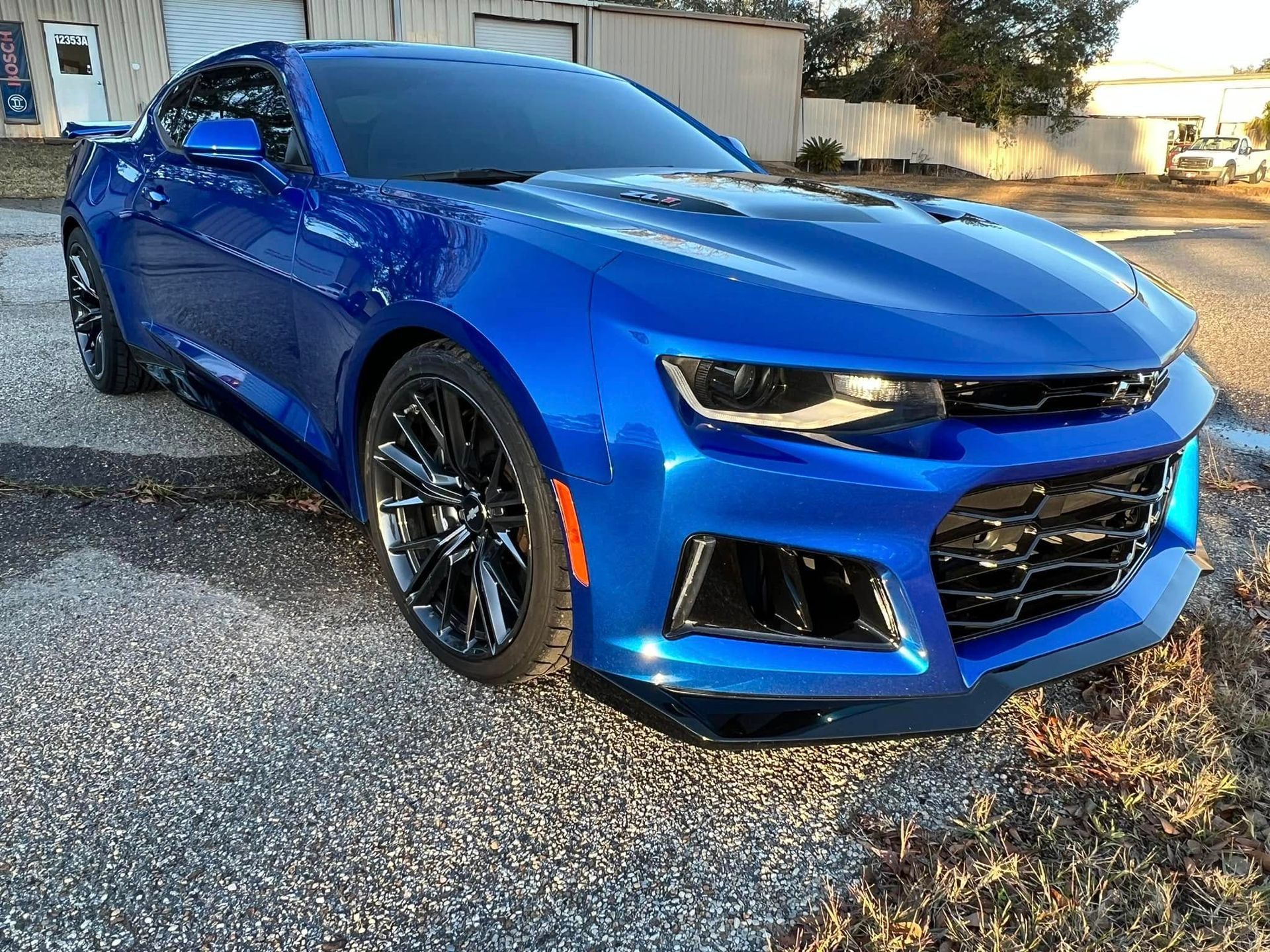A blue chevrolet camaro zl1 is parked on the side of the road.