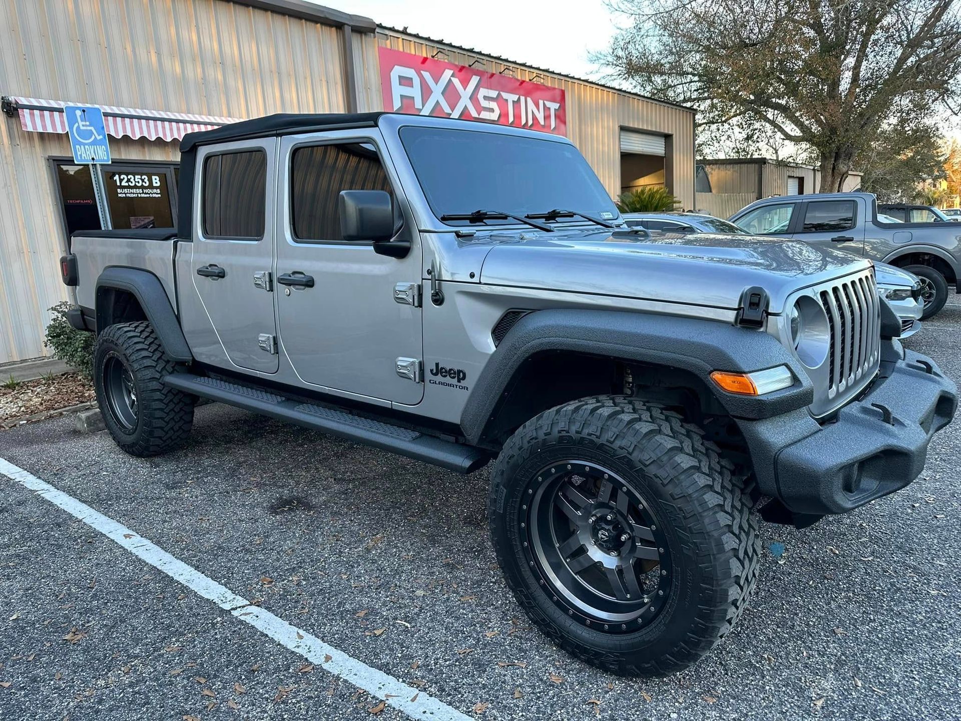 A jeep is parked in a parking lot in front of a building.