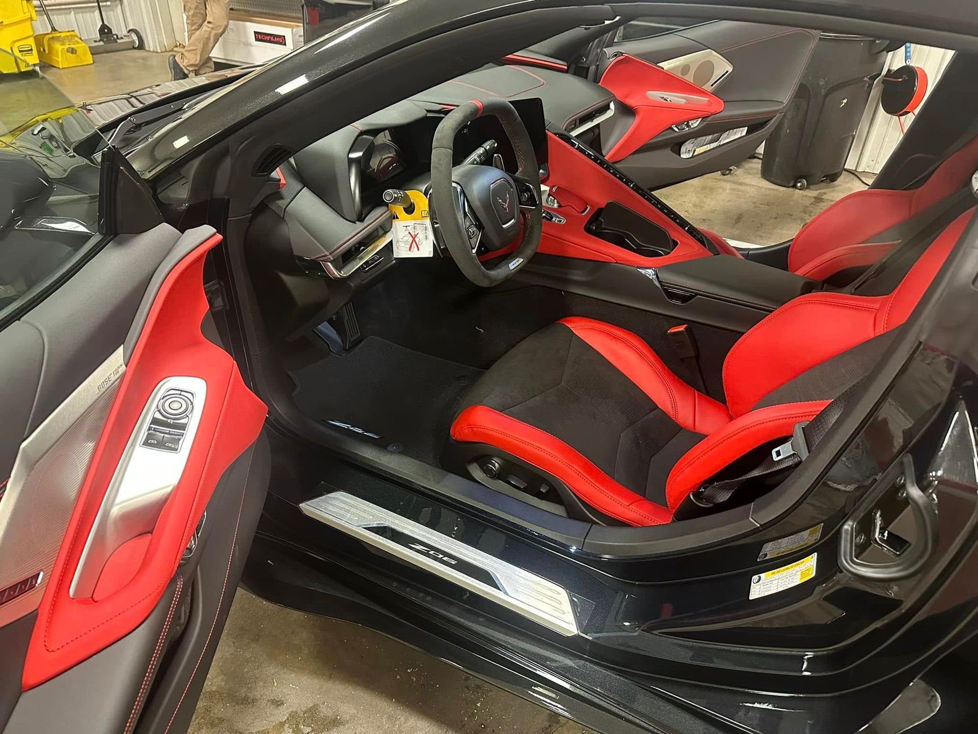 The interior of a black sports car with red seats and a steering wheel.