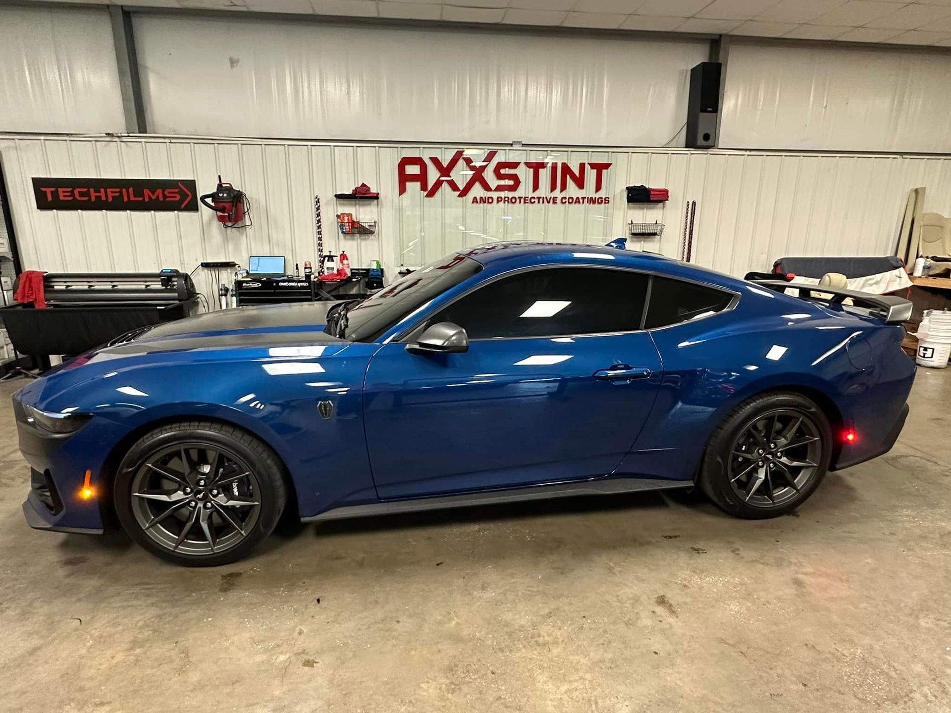 A blue ford mustang is parked in a garage.